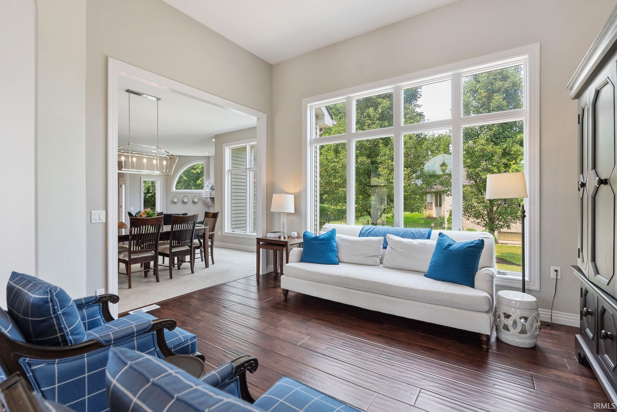 Light-filled living area featuring dark wood-finish flooring and large windows with white trim