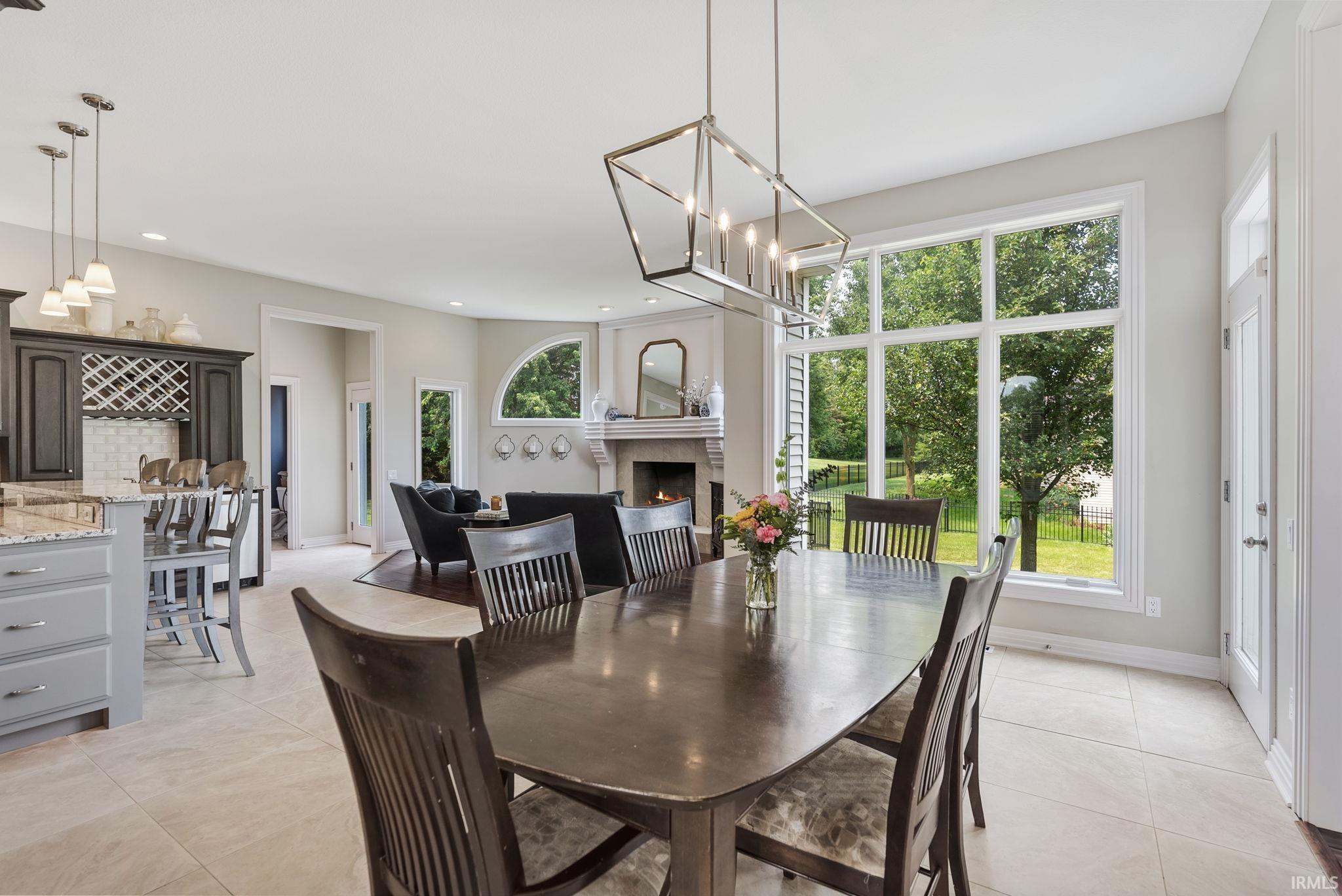 Spacious dining area featuring large windows, a geometric chandelier, and tile flooring