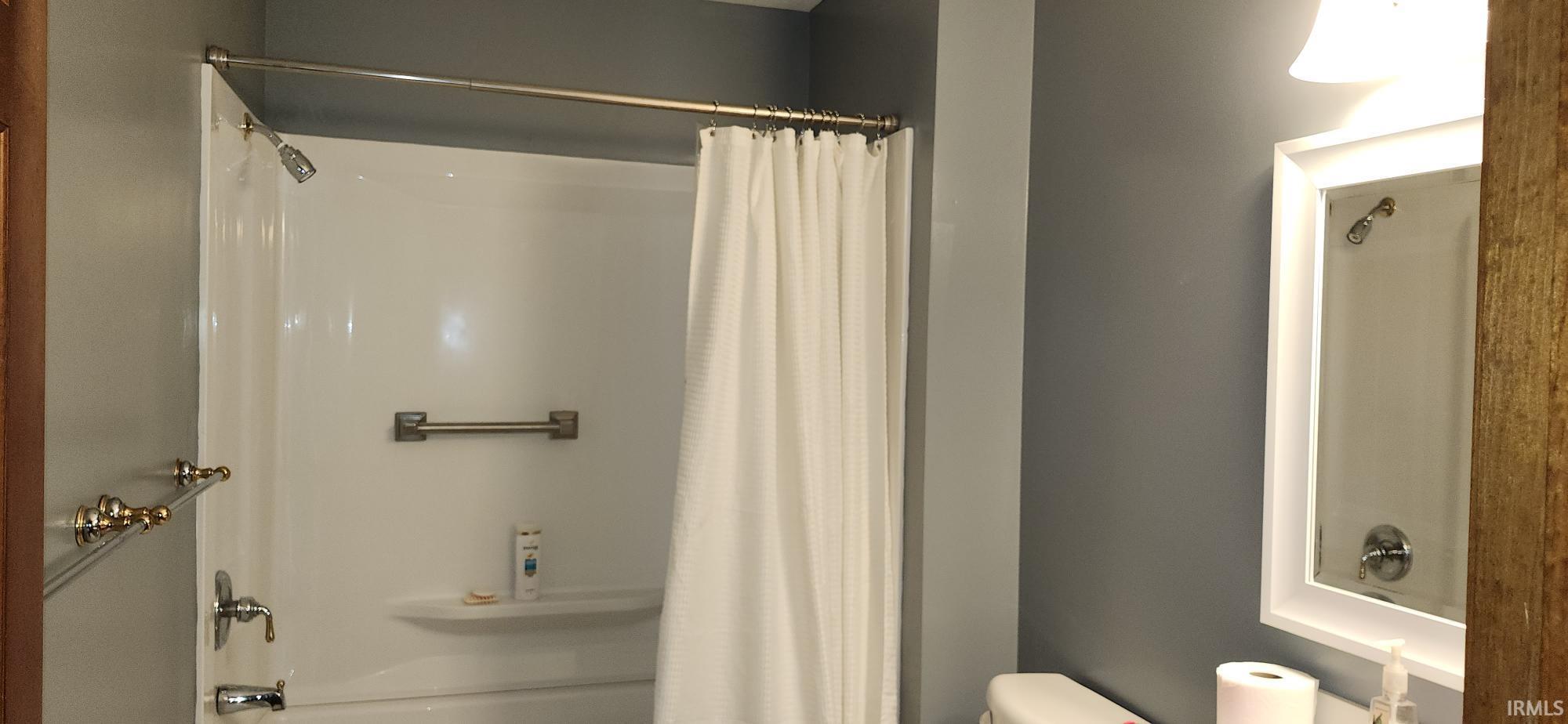 White tub and shower combination with a curved shower rod