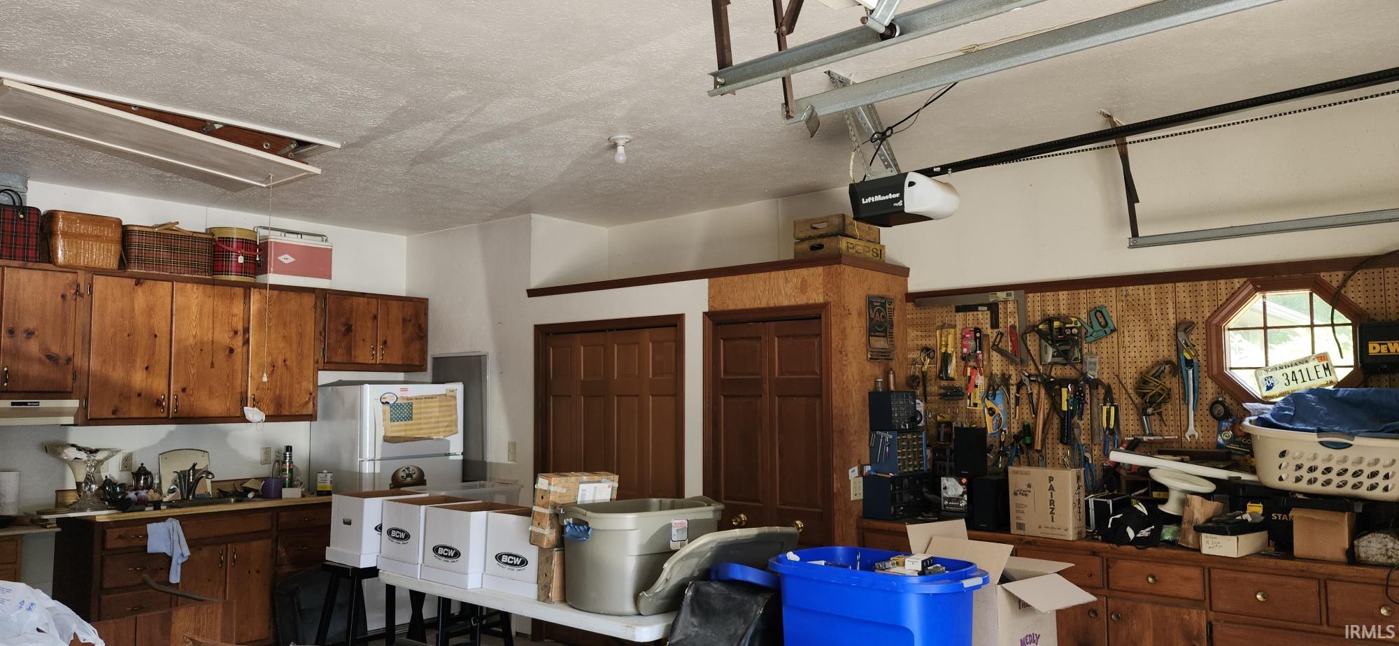 Garage space featuring extensive wood cabinetry, pegboard storage, and a built-in hexagonal window