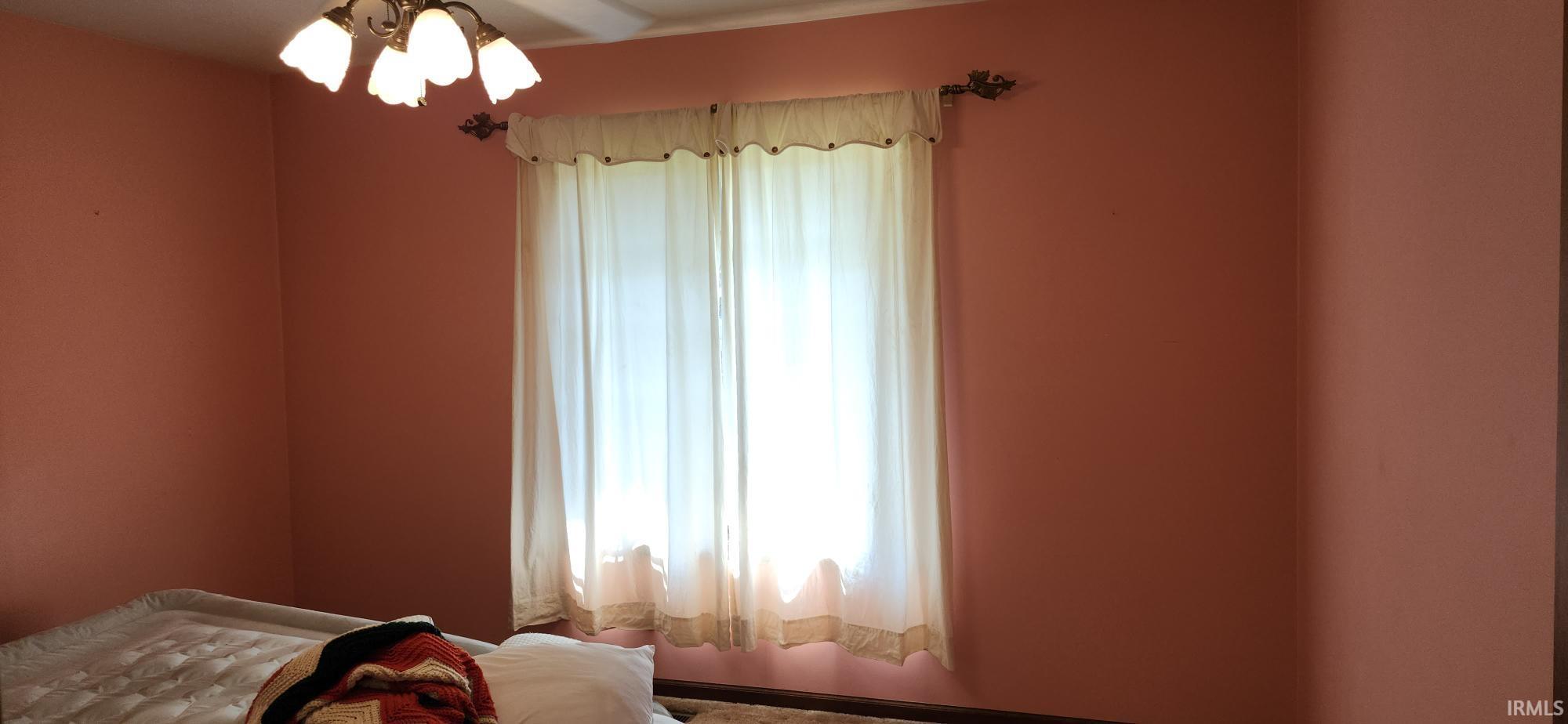 Window with sheer curtains, a decorative curtain rod, and a four-light ceiling fixture