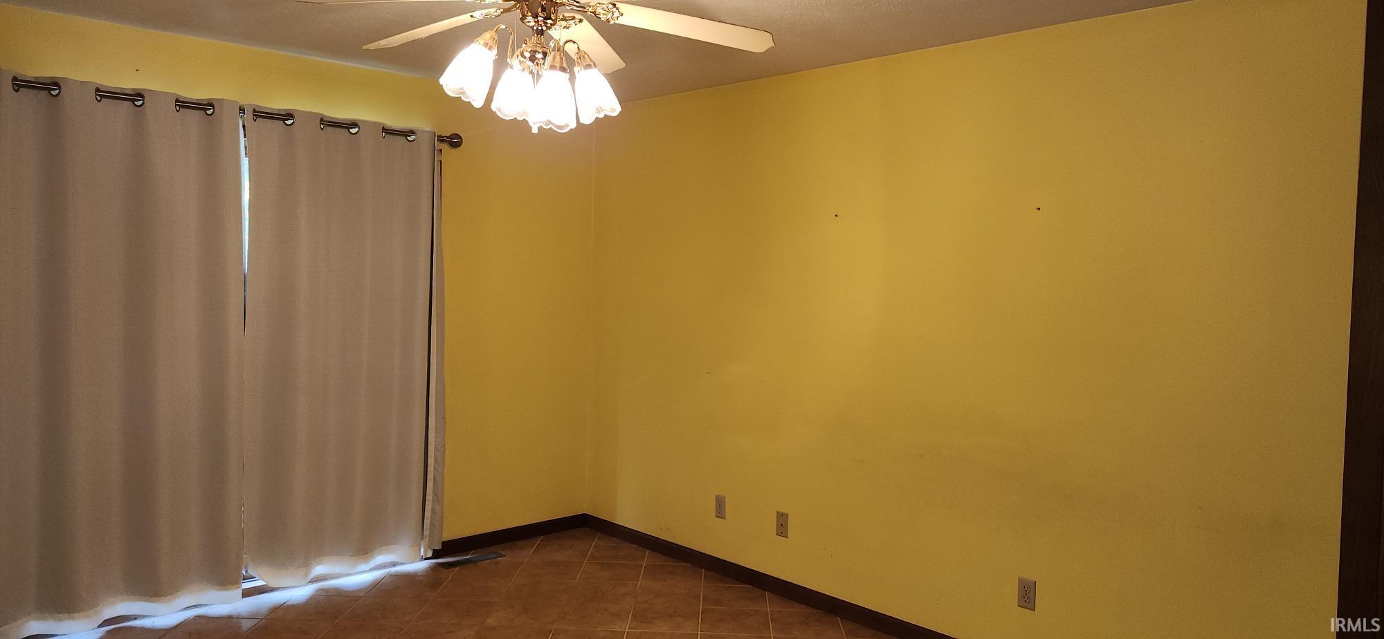 Room with yellow painted walls, a ceiling fan with integrated lighting, and tile flooring