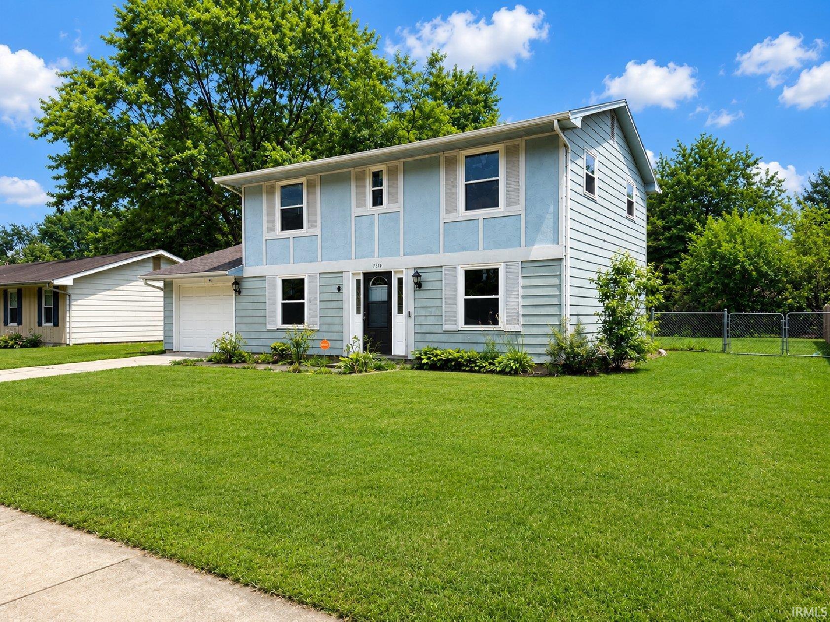 Two-story residence featuring light blue siding, white window shutters, and an attached single-car garage