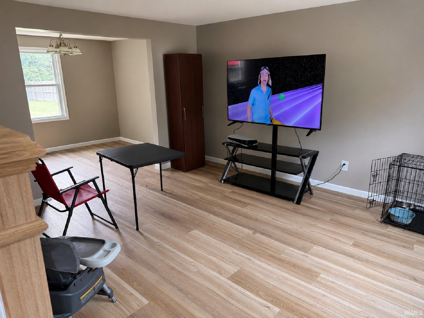 Open-concept living area featuring wood-finish flooring, neutral wall tones, and an arched entryway