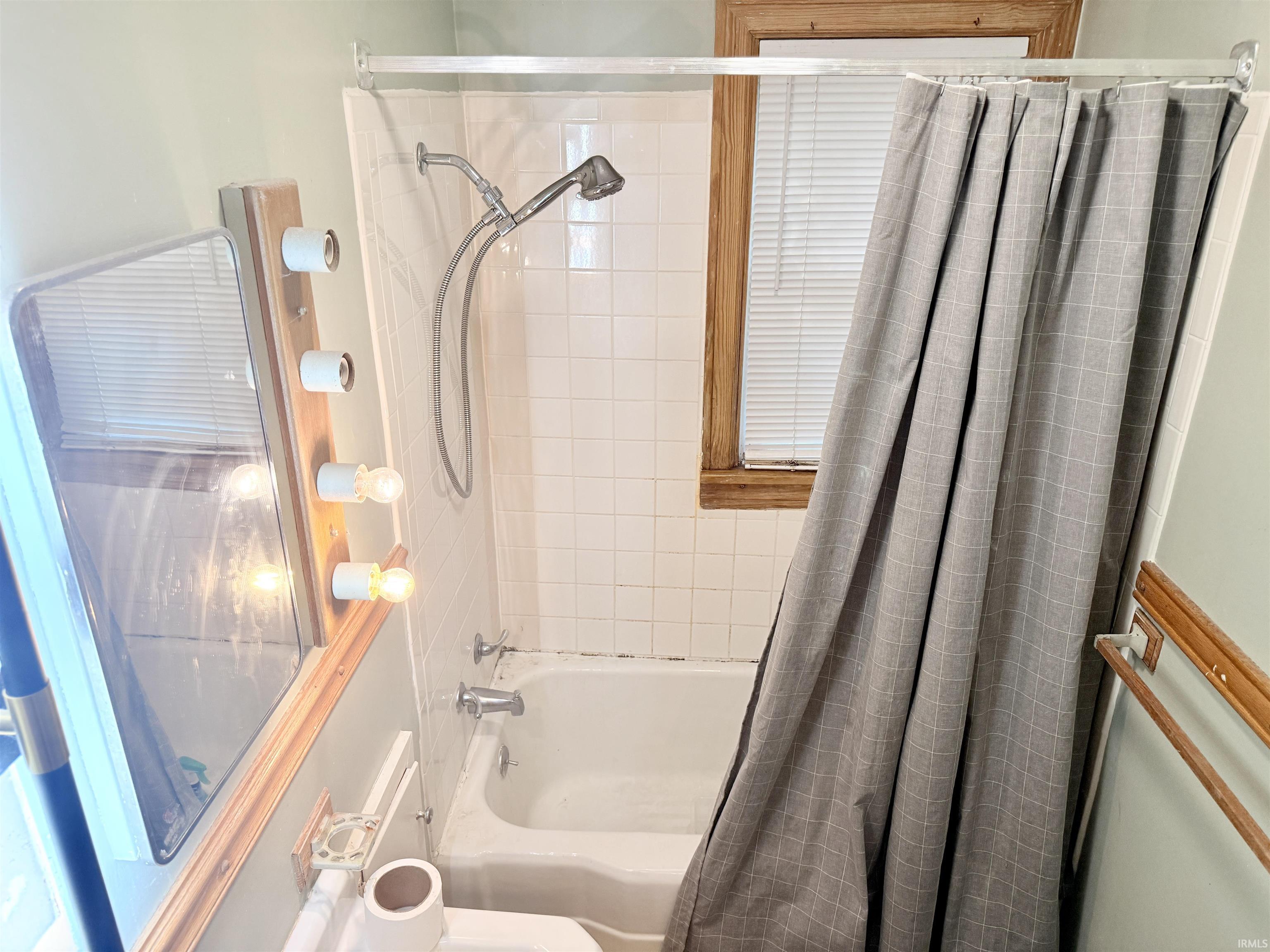 Bathroom featuring a white tiled shower/tub combination with a wall-mounted shower head