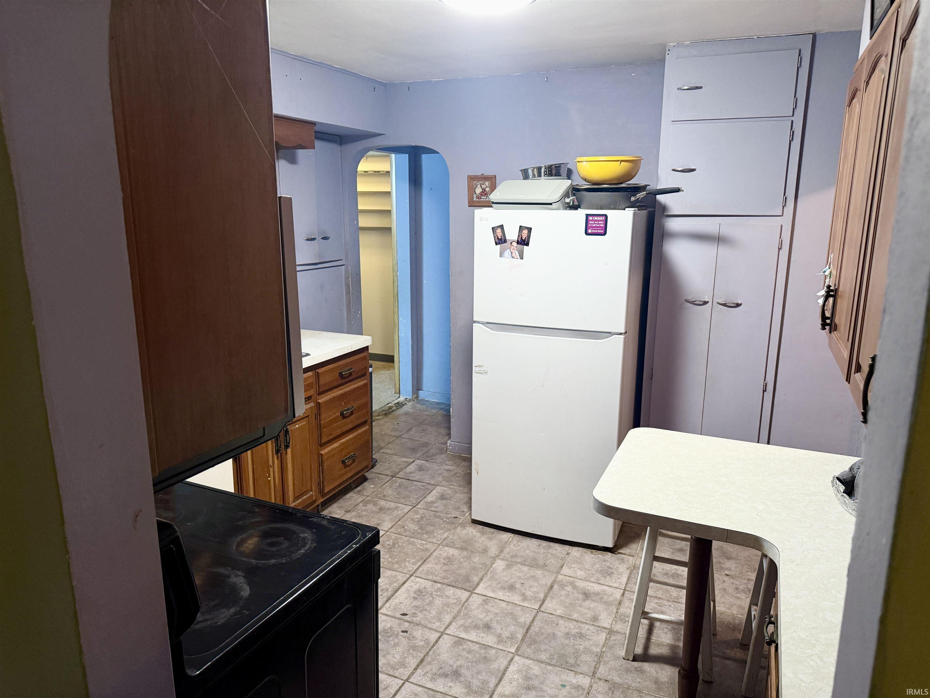 Kitchen featuring wood-finish cabinetry, tile flooring, and integrated white appliances
