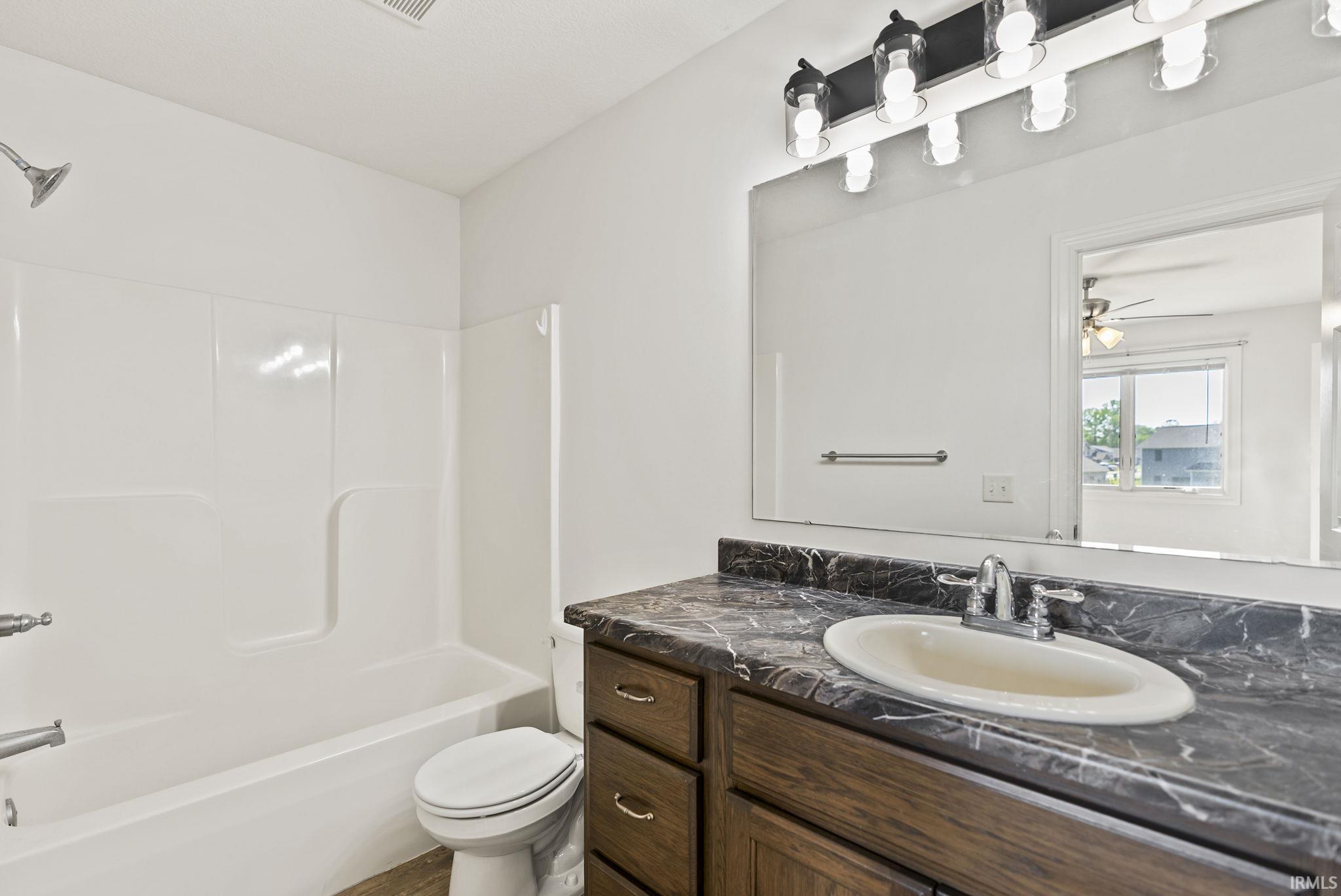 Bathroom featuring a wood-finish vanity with an integrated sink, a dark countertop, and a wide mirror