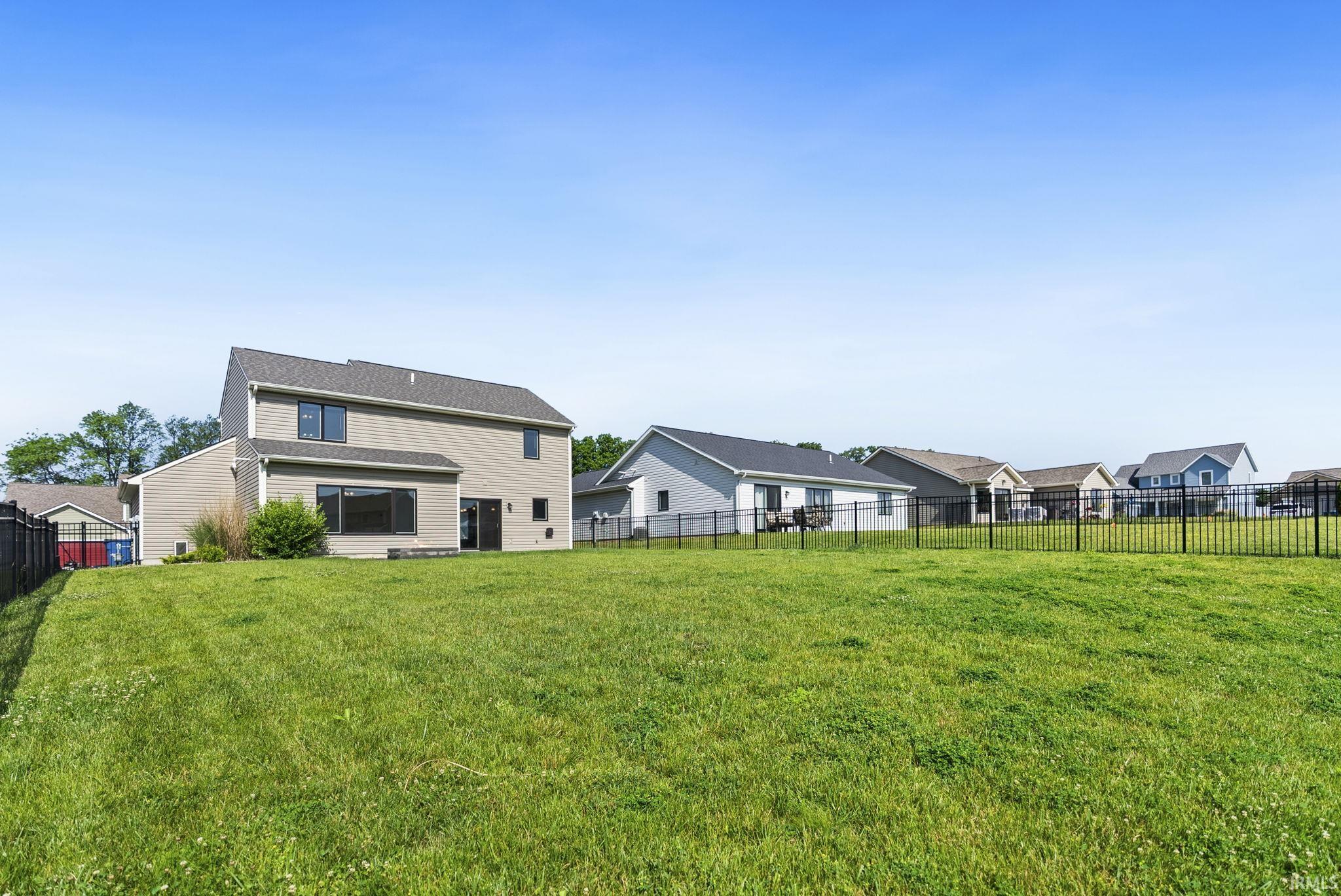 Expansive green lawn with a black metal fence perimeter