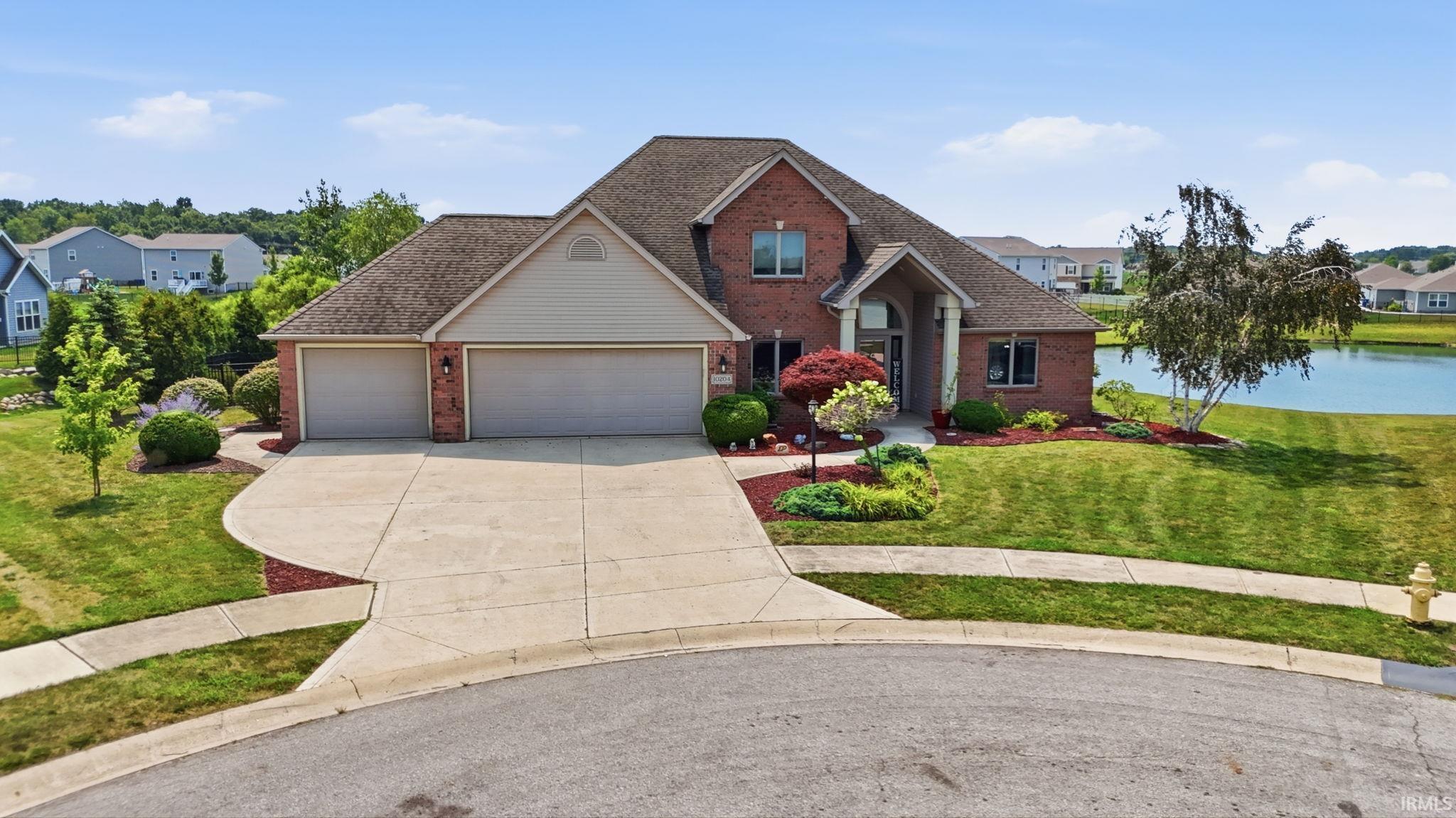 Brick exterior residence featuring a two-car garage, concrete driveway, and front lawn landscaping