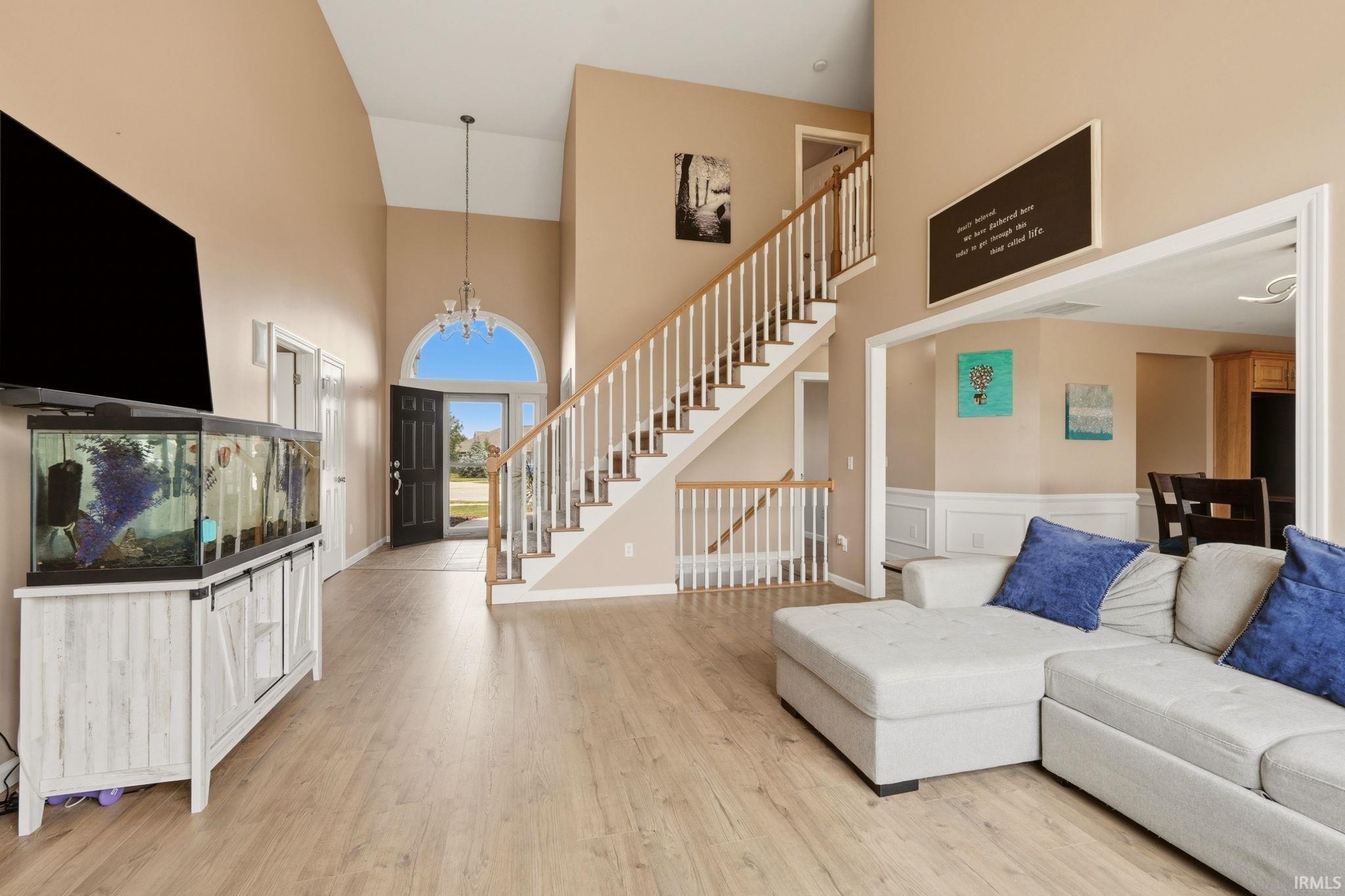 Two-story foyer with high ceilings, light wood-finish flooring, and a chandelier