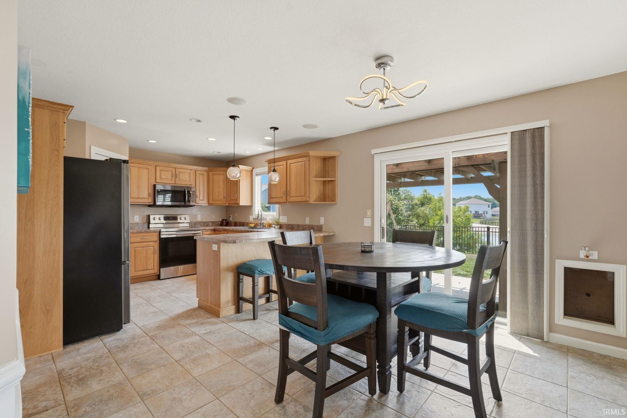 Open-concept kitchen featuring light wood cabinetry, stainless steel appliances, recessed lighting, and tile flooring