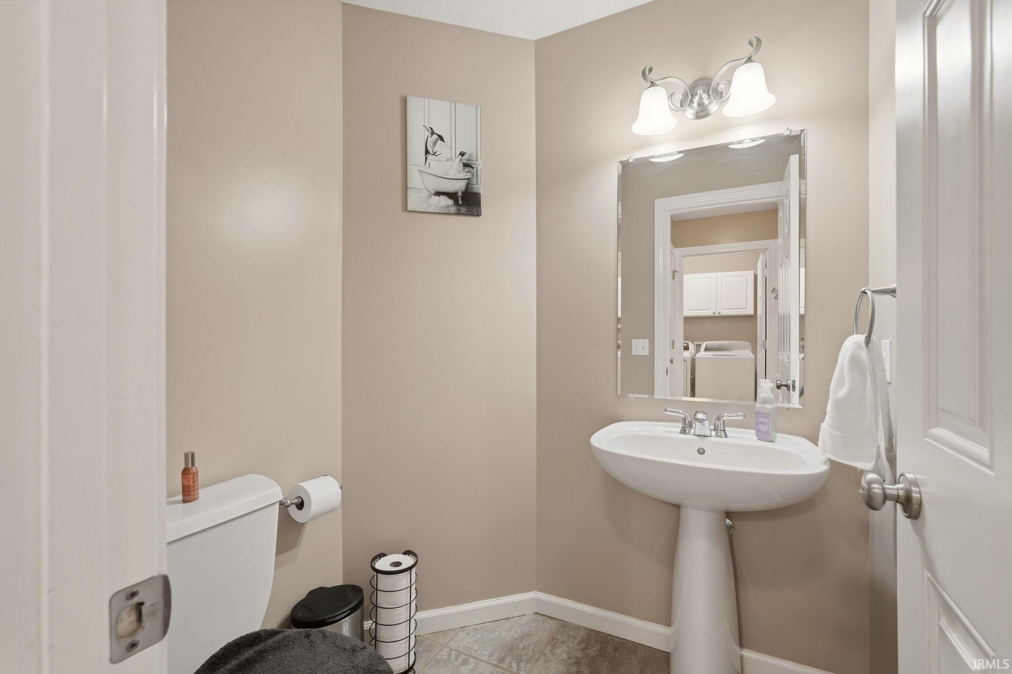 Pedestal sink with chrome fixtures, framed mirror, and two-light vanity fixture
