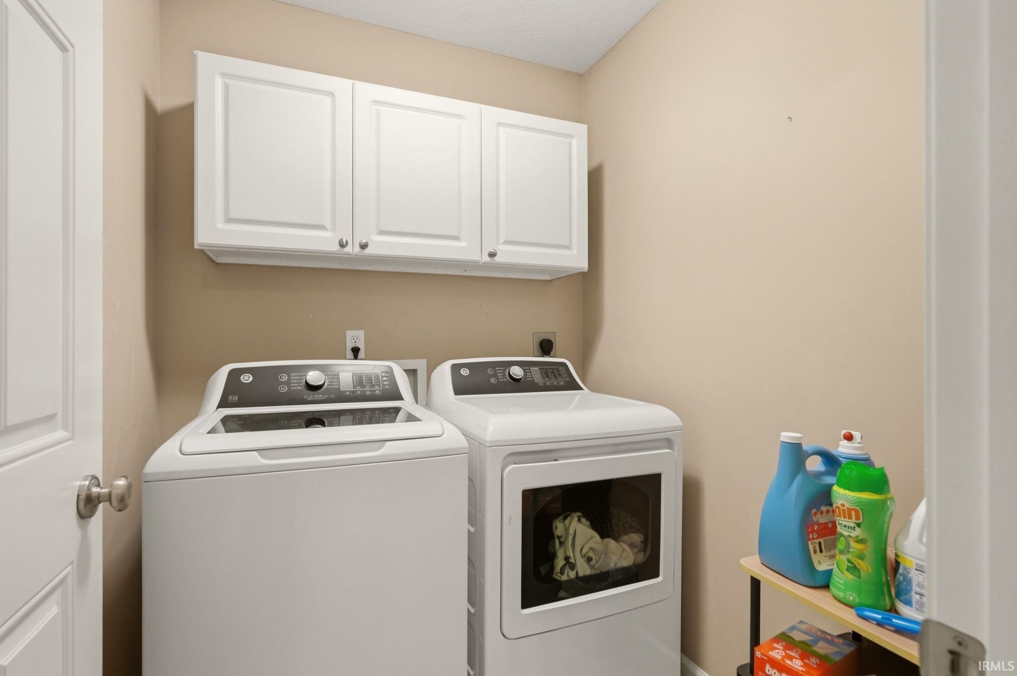 Dedicated laundry area featuring white shaker-style cabinetry, overhead storage, and neutral wall tones
