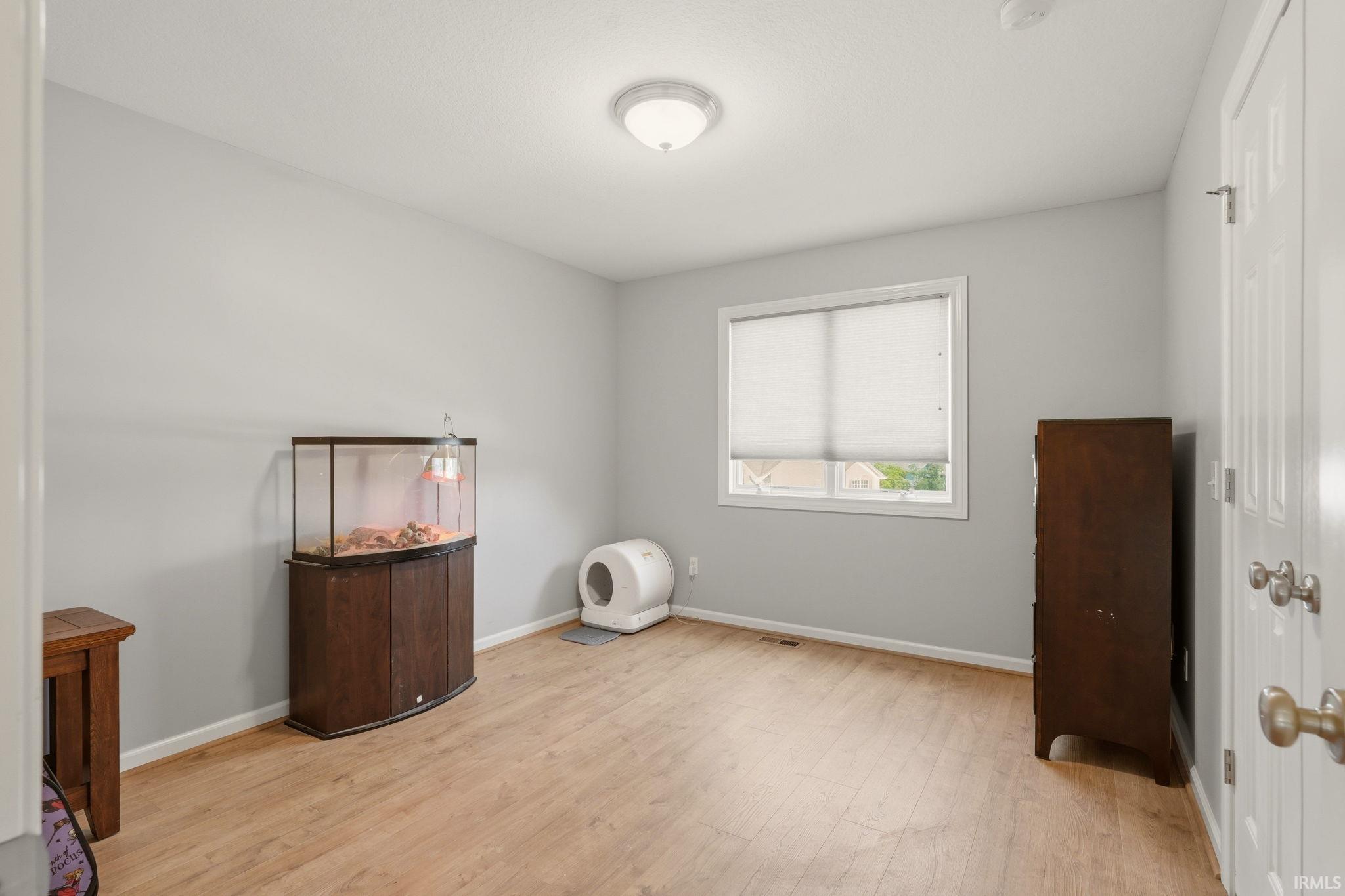 Room featuring wood-finish flooring, light gray wall paint, and a window with white blinds