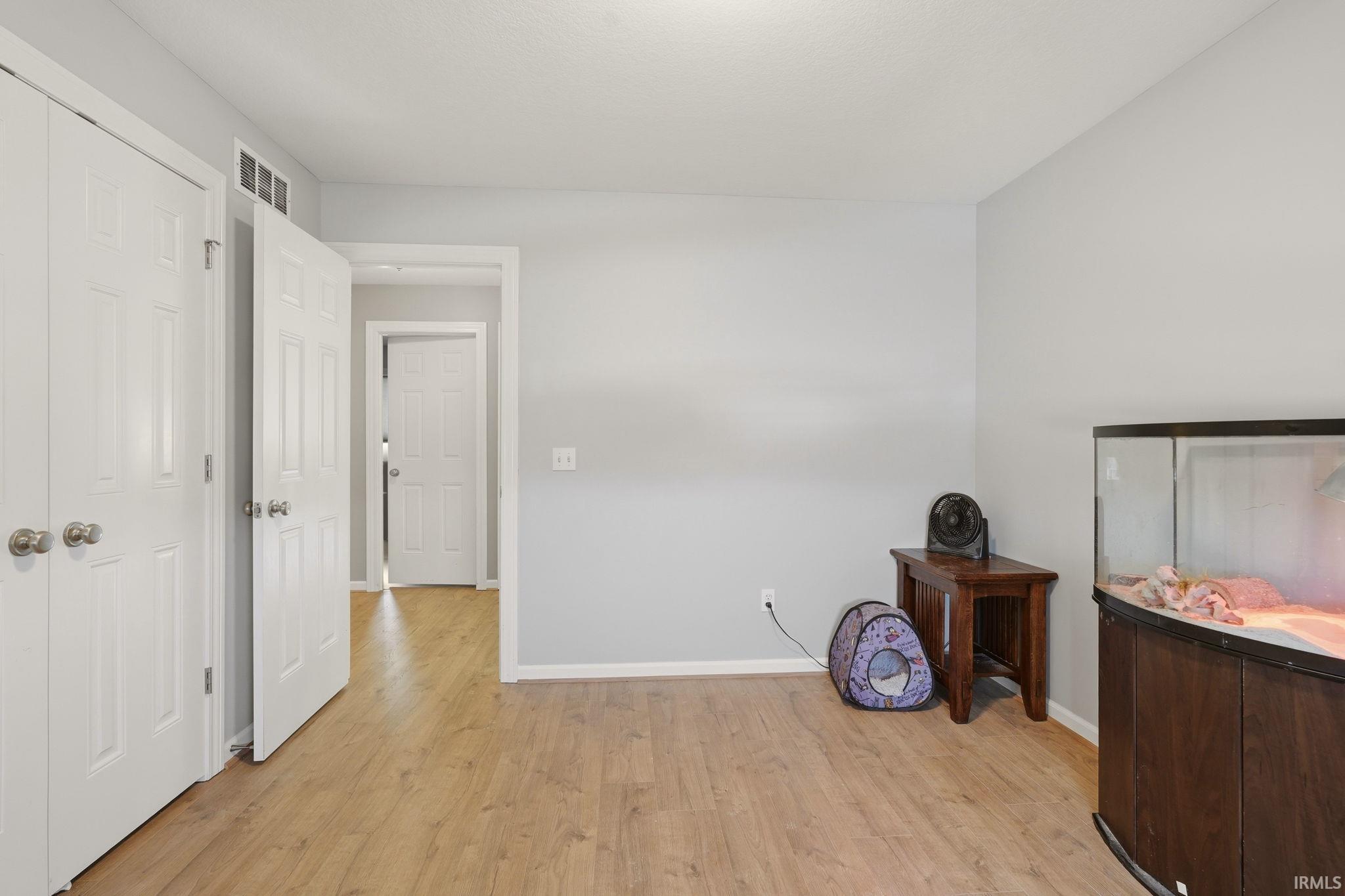 Room with wood-finish flooring, light gray walls, and white trim