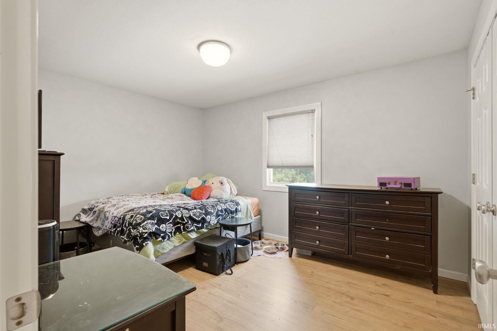 Light-filled room featuring wood-finish flooring, neutral wall tones, and a window with a roller blind