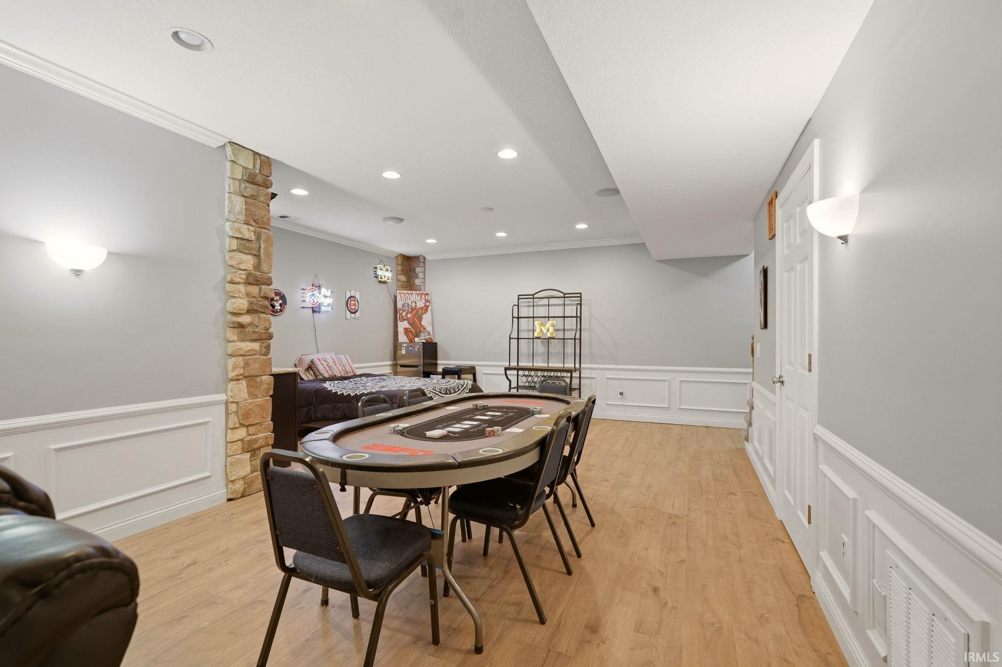 Recreation room featuring wood-finish flooring, wainscoting, recessed lighting, and a stone accent column