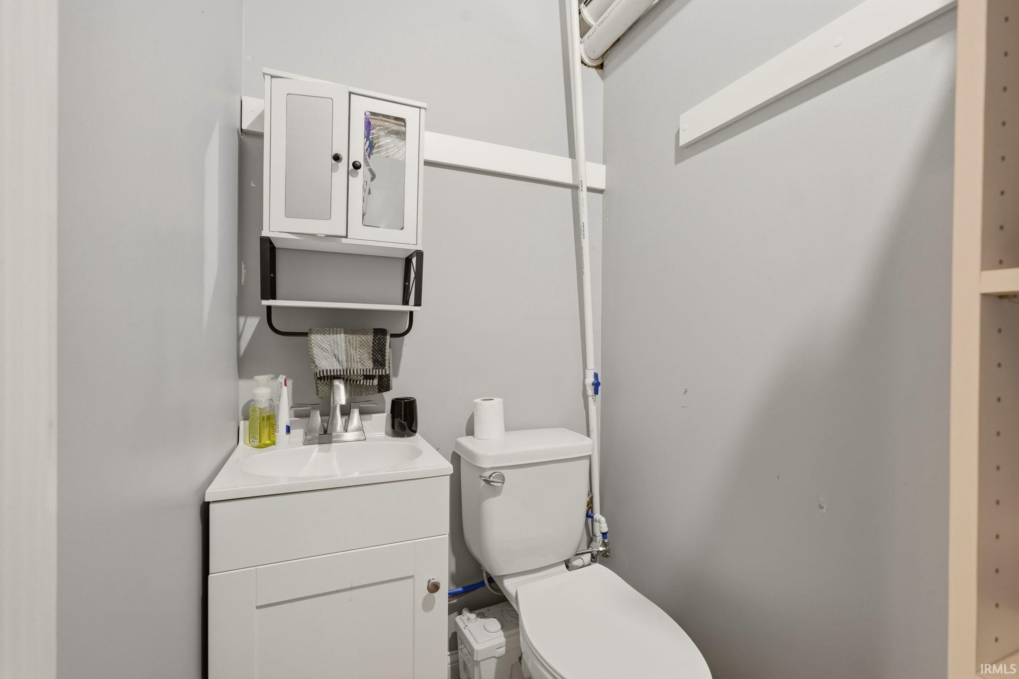 Compact bathroom featuring a white corner vanity with an integrated sink, a matching white medicine cabinet, and a standard toilet