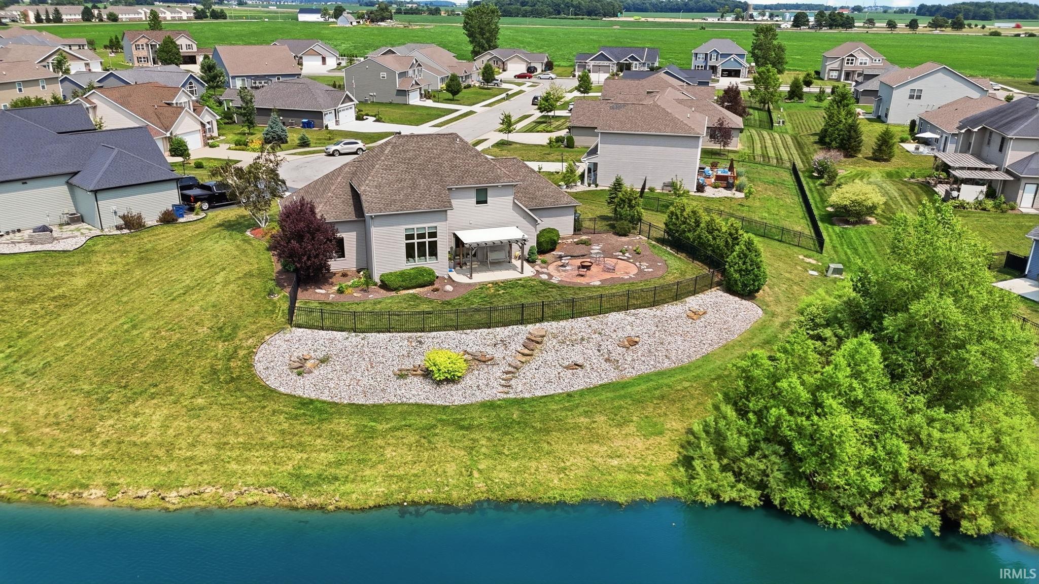 Rear exterior featuring a stone patio with fire pit, an awning-covered outdoor dining area, and a fenced backyard
