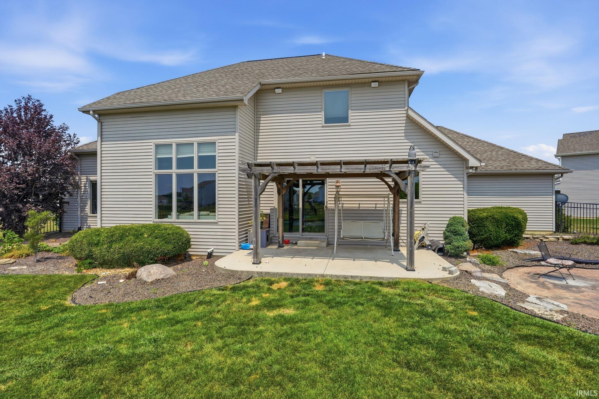 Rear exterior featuring light-toned horizontal siding, a gabled roofline, and a concrete patio
