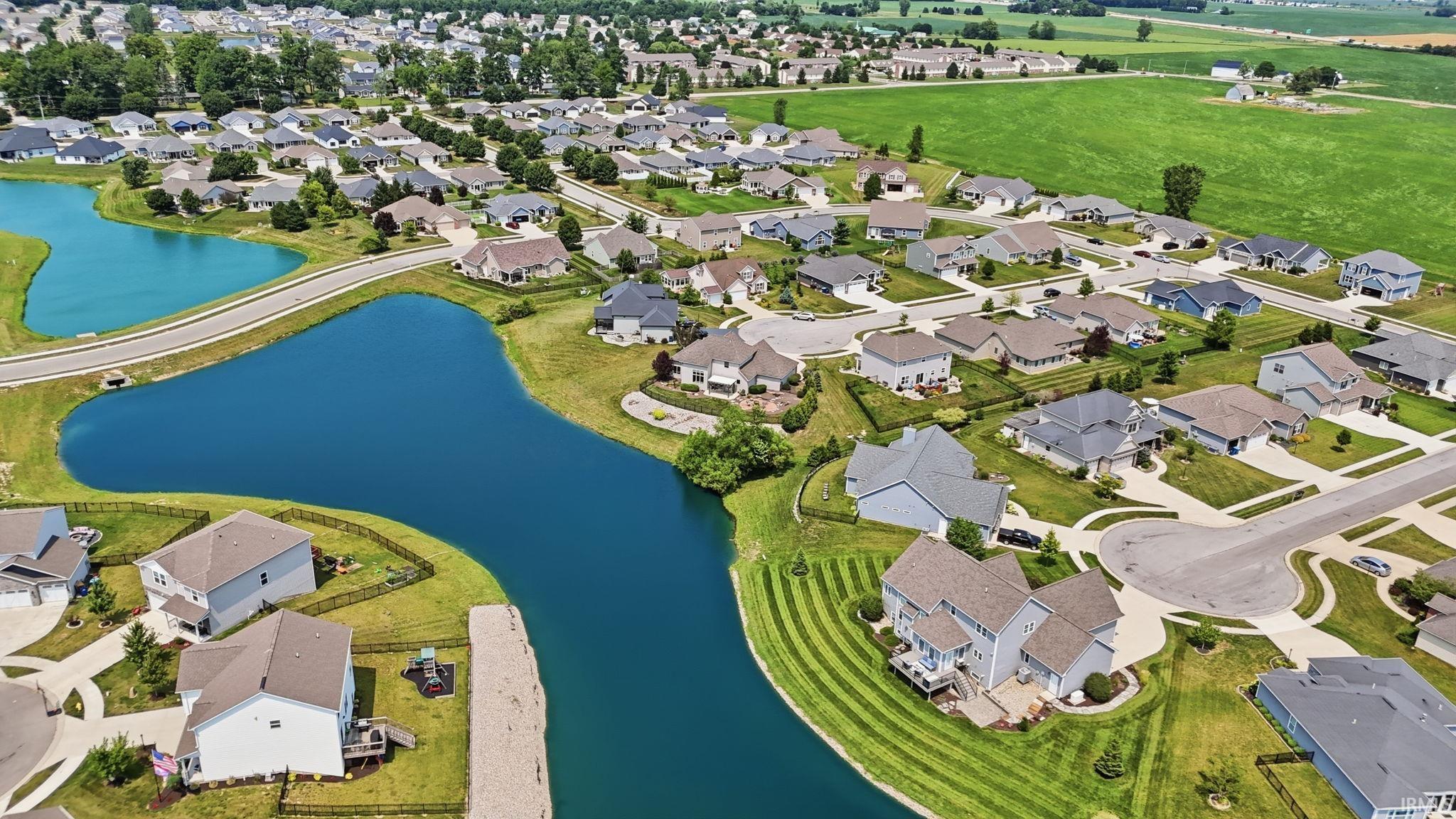 Residential development featuring detached homes with varied architectural styles, manicured lawns, and mature trees