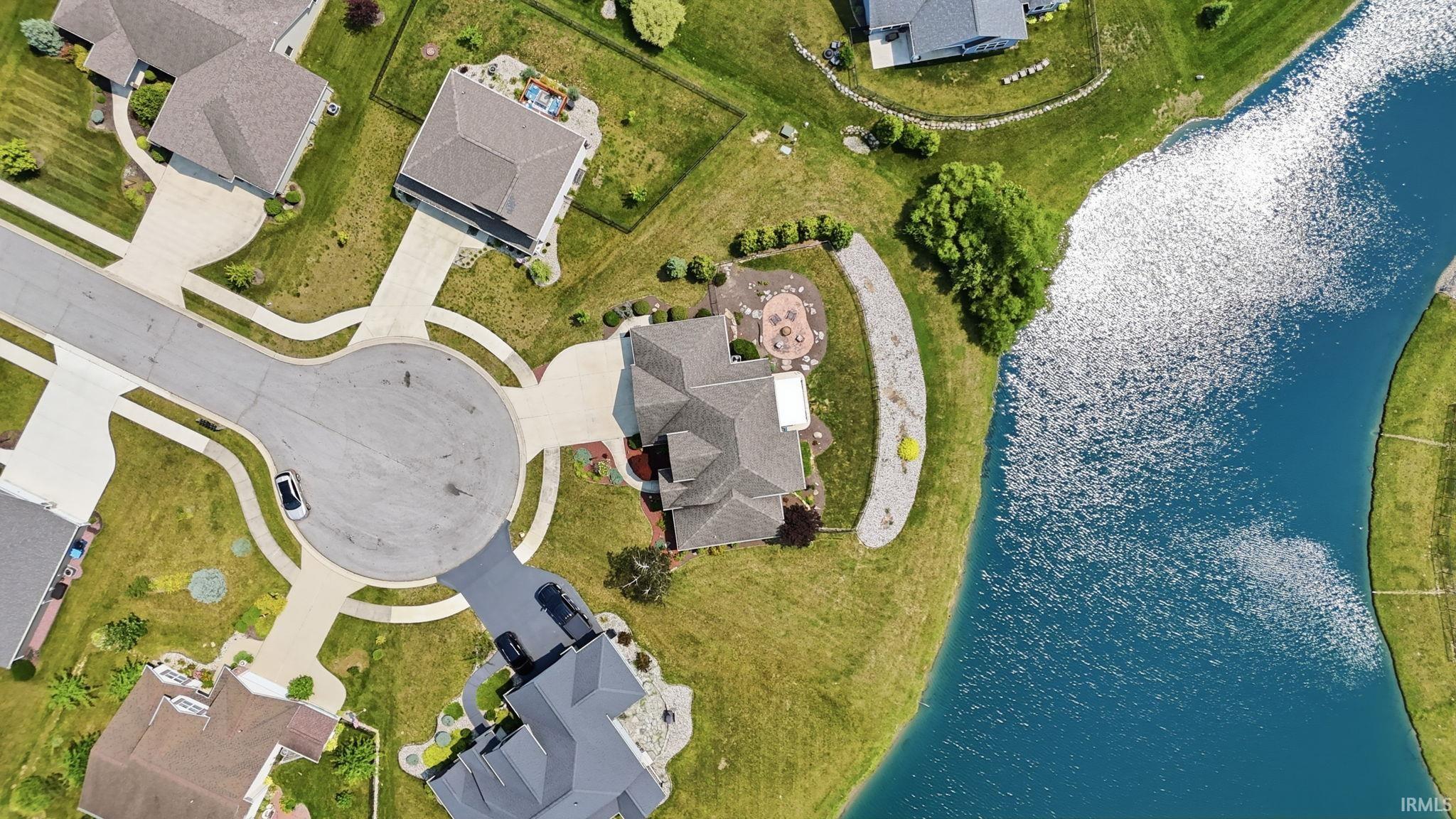 Aerial view showcasing a residential property situated along a waterway, featuring a cul-de-sac street pattern