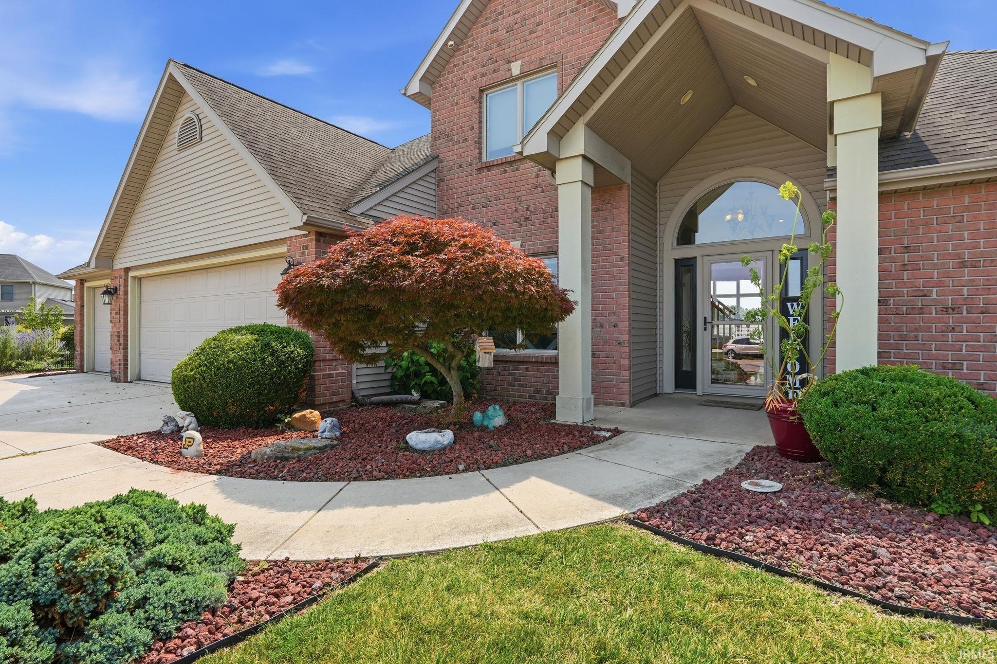 Brick facade residence featuring an arched portico entry with sidelights and an arched transom window