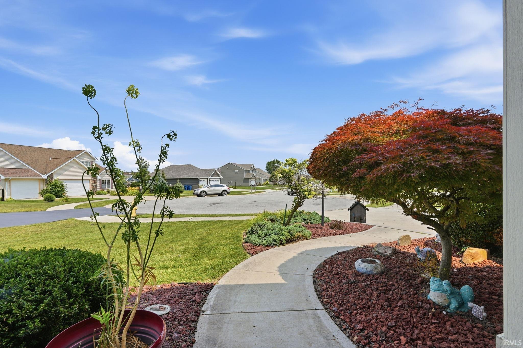 Curved concrete walkway featuring landscape lighting and red rock ground cover