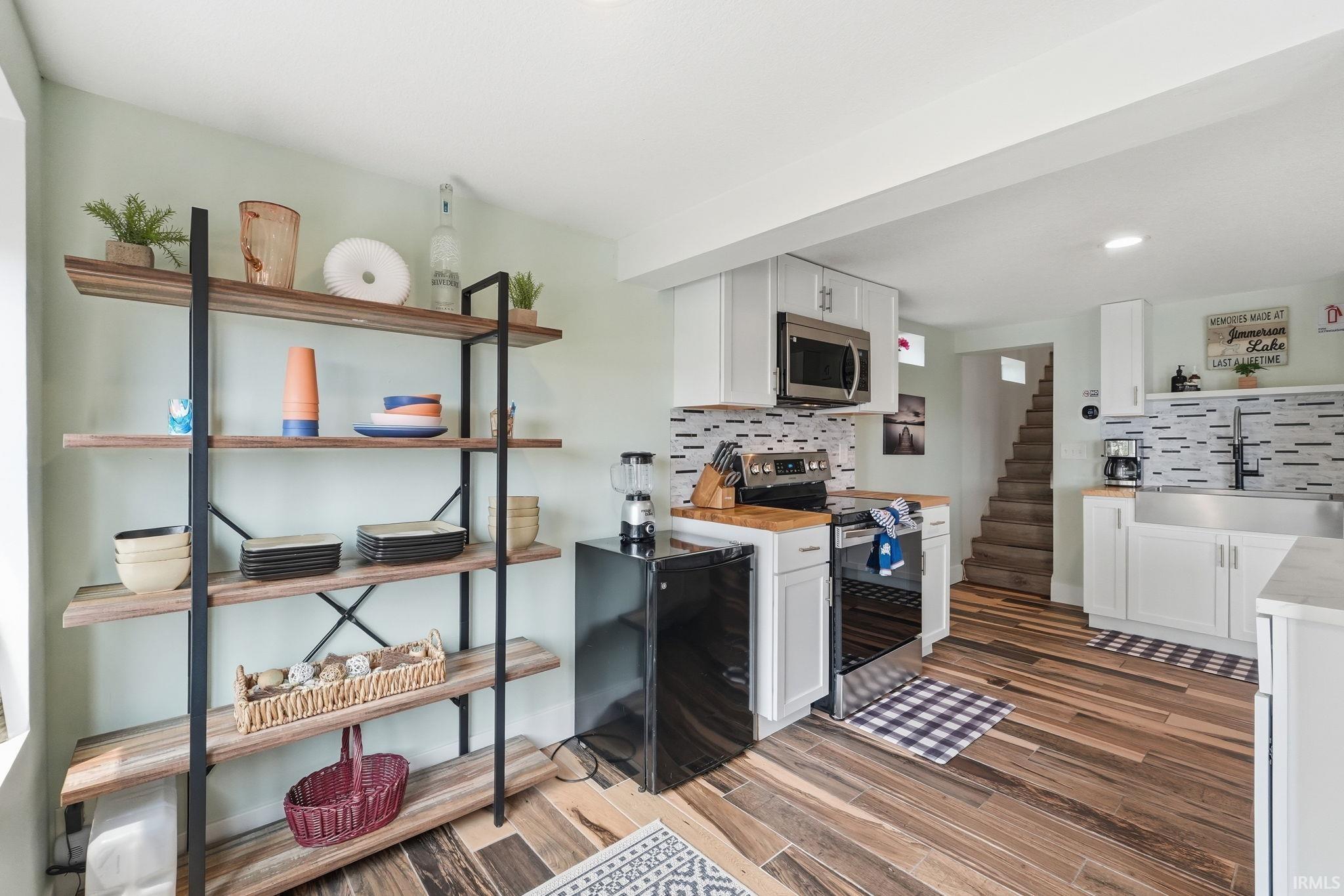 Contemporary kitchen space featuring wood-finish flooring, white cabinetry, and a patterned tile backsplash