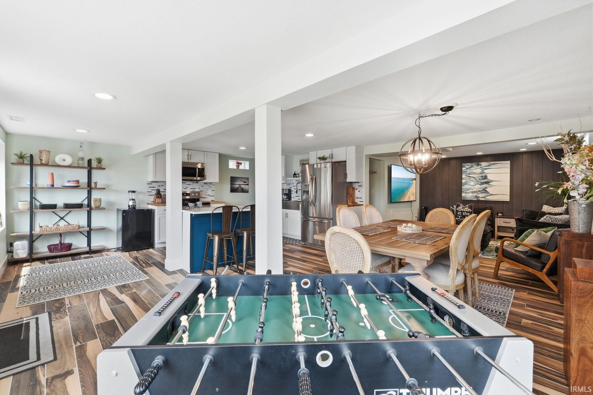 Spacious open-concept lower level featuring wood-finish flooring, recessed lighting, and a partial kitchen with a blue island