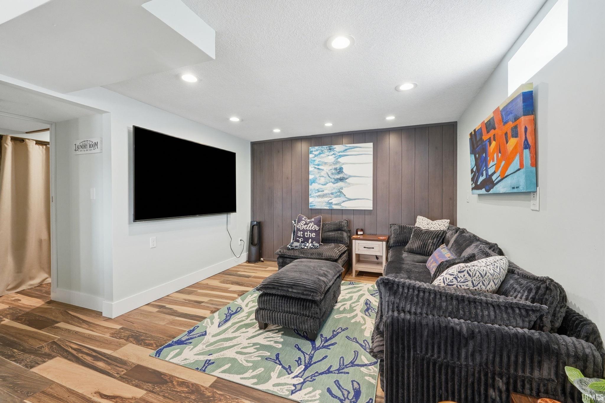 Entertainment space featuring wood-finish flooring, recessed lighting, and a dark paneled accent wall