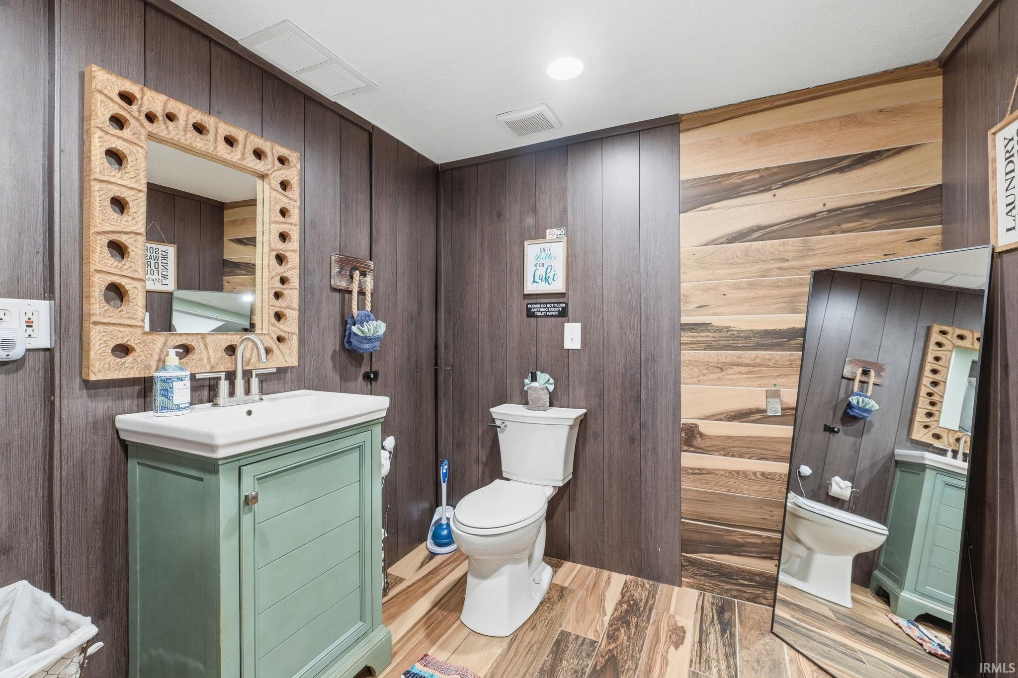 Bathroom featuring wood-finish wall panels and complementary wood-finish flooring