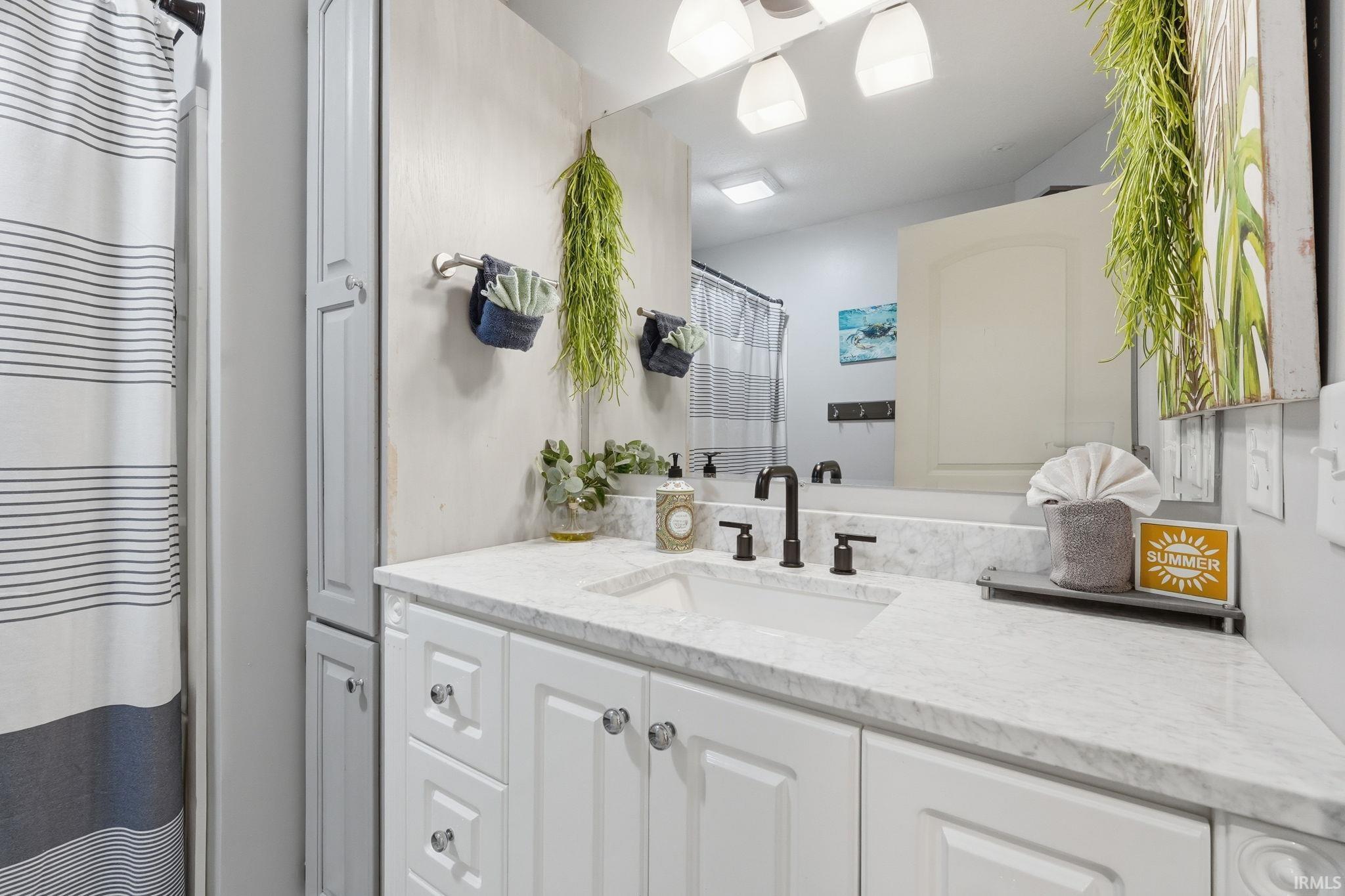 Bathroom featuring a white vanity with paneling, a rectangular undermount sink, and a dark-finish faucet
