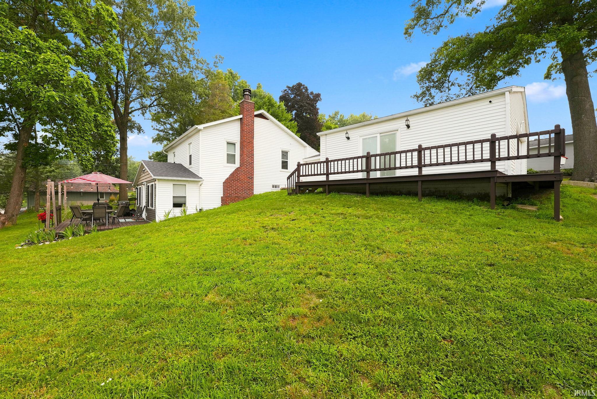 Spacious green lawn with mature trees and a multi-level deck system