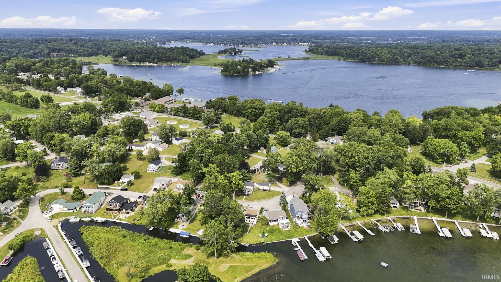 Expansive aerial perspective showcasing a community situated along a large body of water, featuring numerous waterfront properties