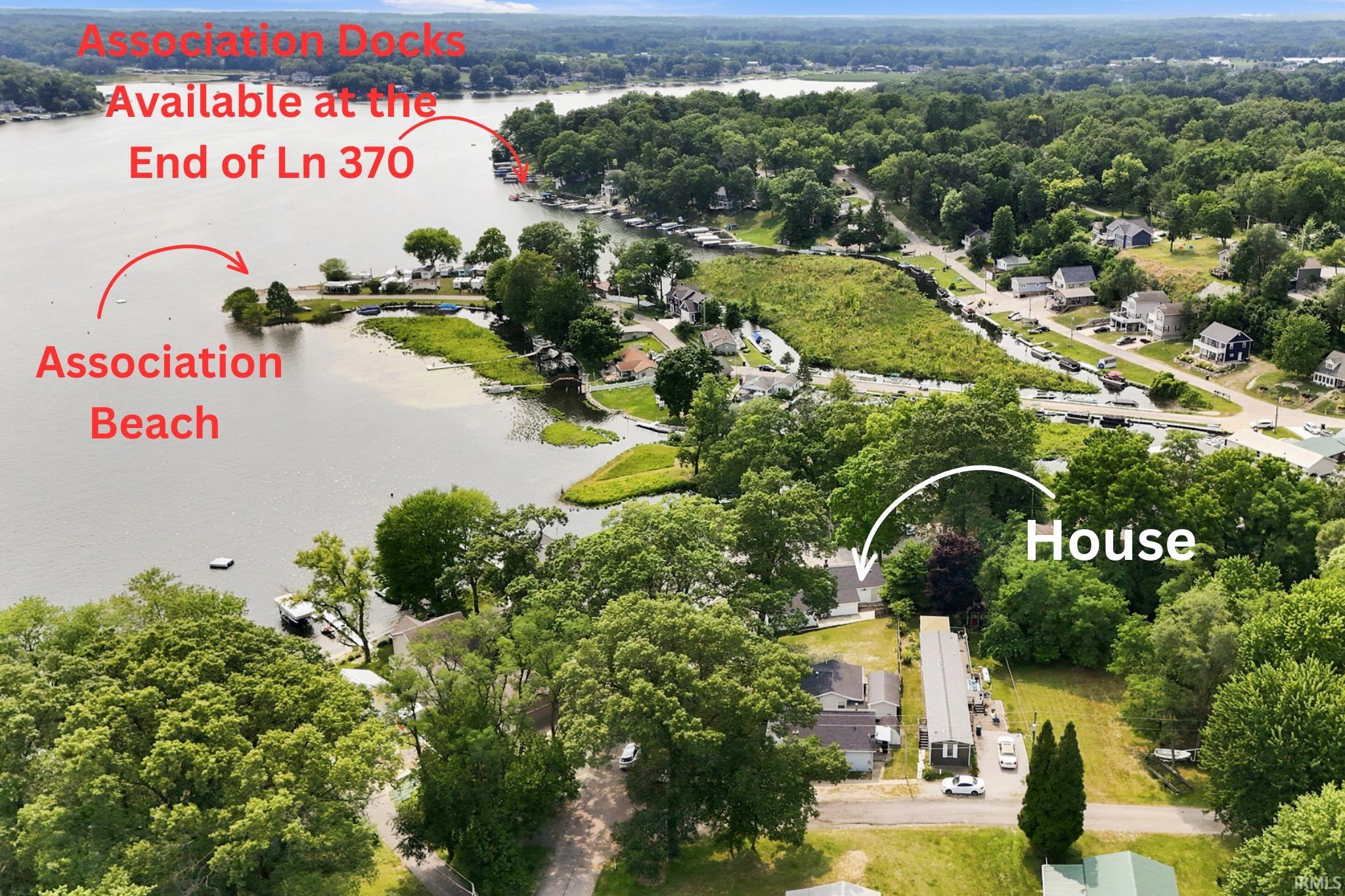Aerial perspective showcasing a residential property nestled among lush trees, with a prominent body of water nearby