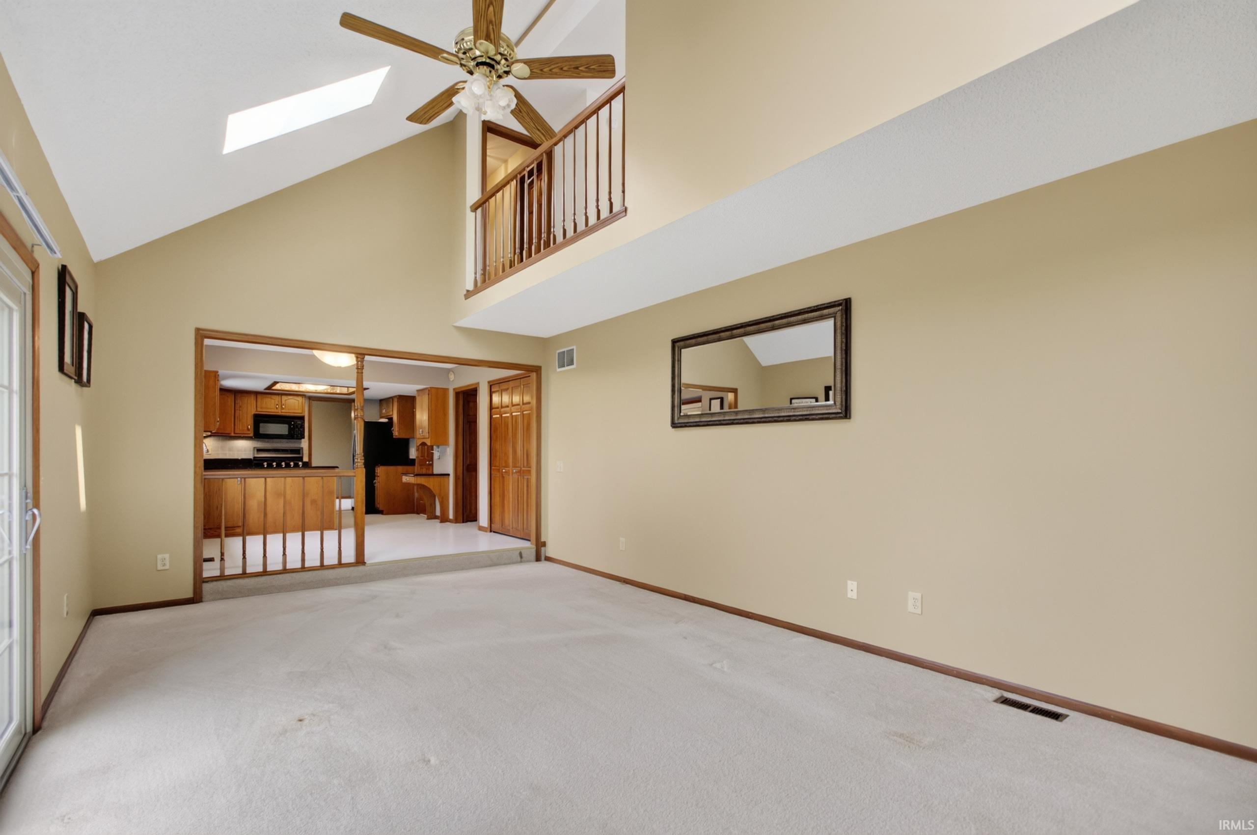 Living space featuring vaulted ceilings, a skylight, and a ceiling fan