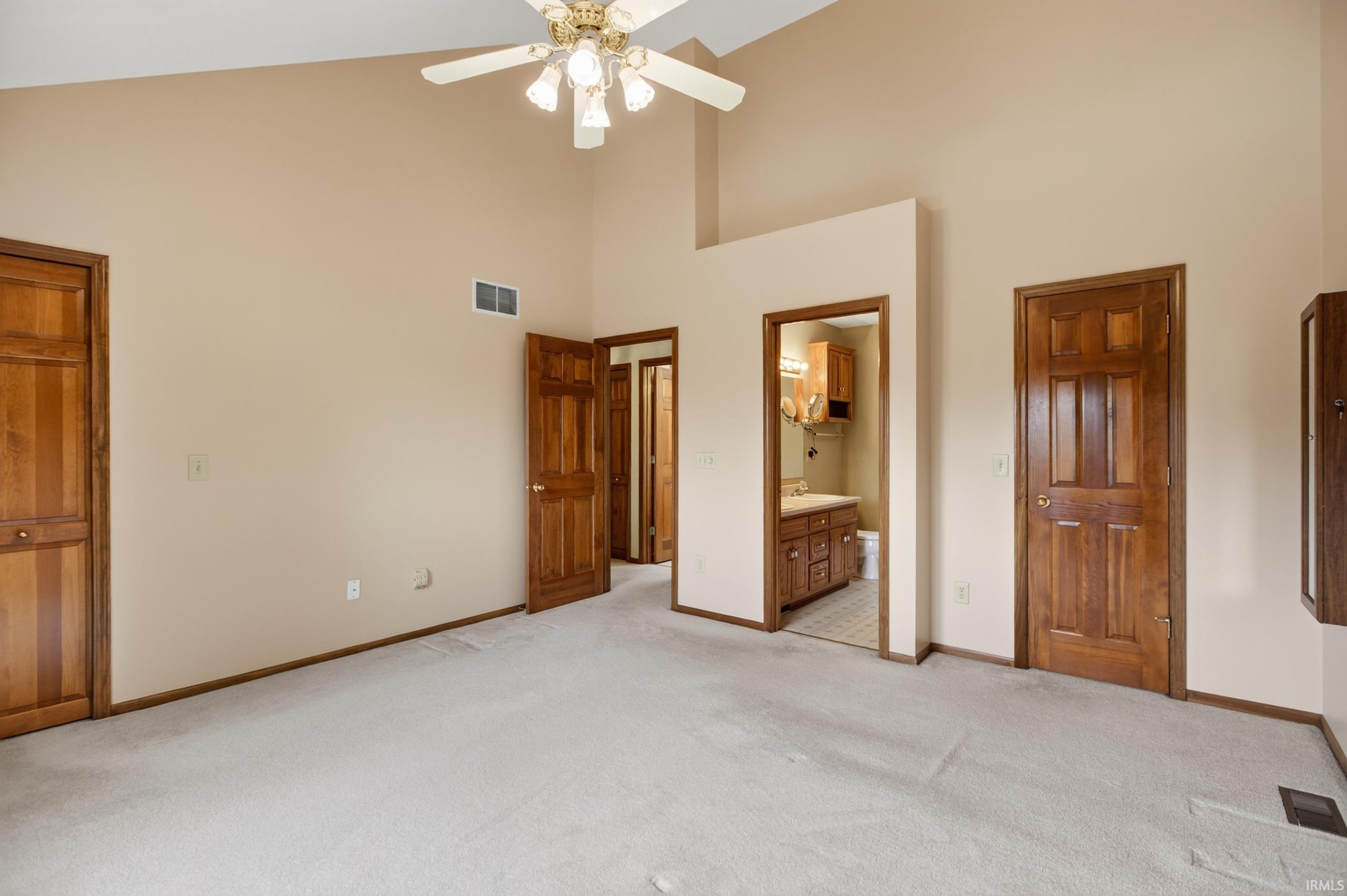 Carpeted room featuring a vaulted ceiling and a ceiling fan with integrated lighting