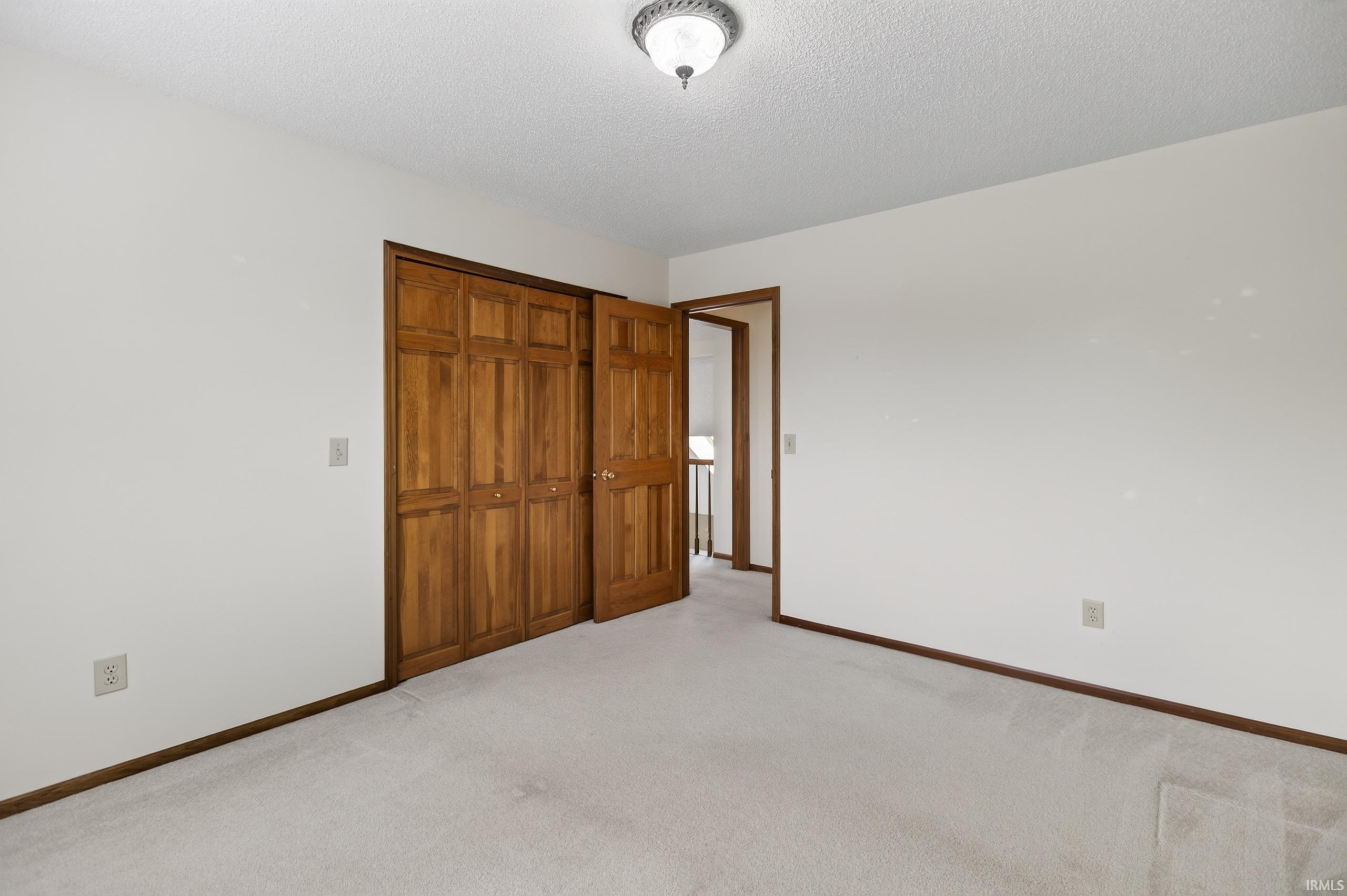 Bedroom featuring light-colored carpet, white walls, and a ceiling-mounted light fixture