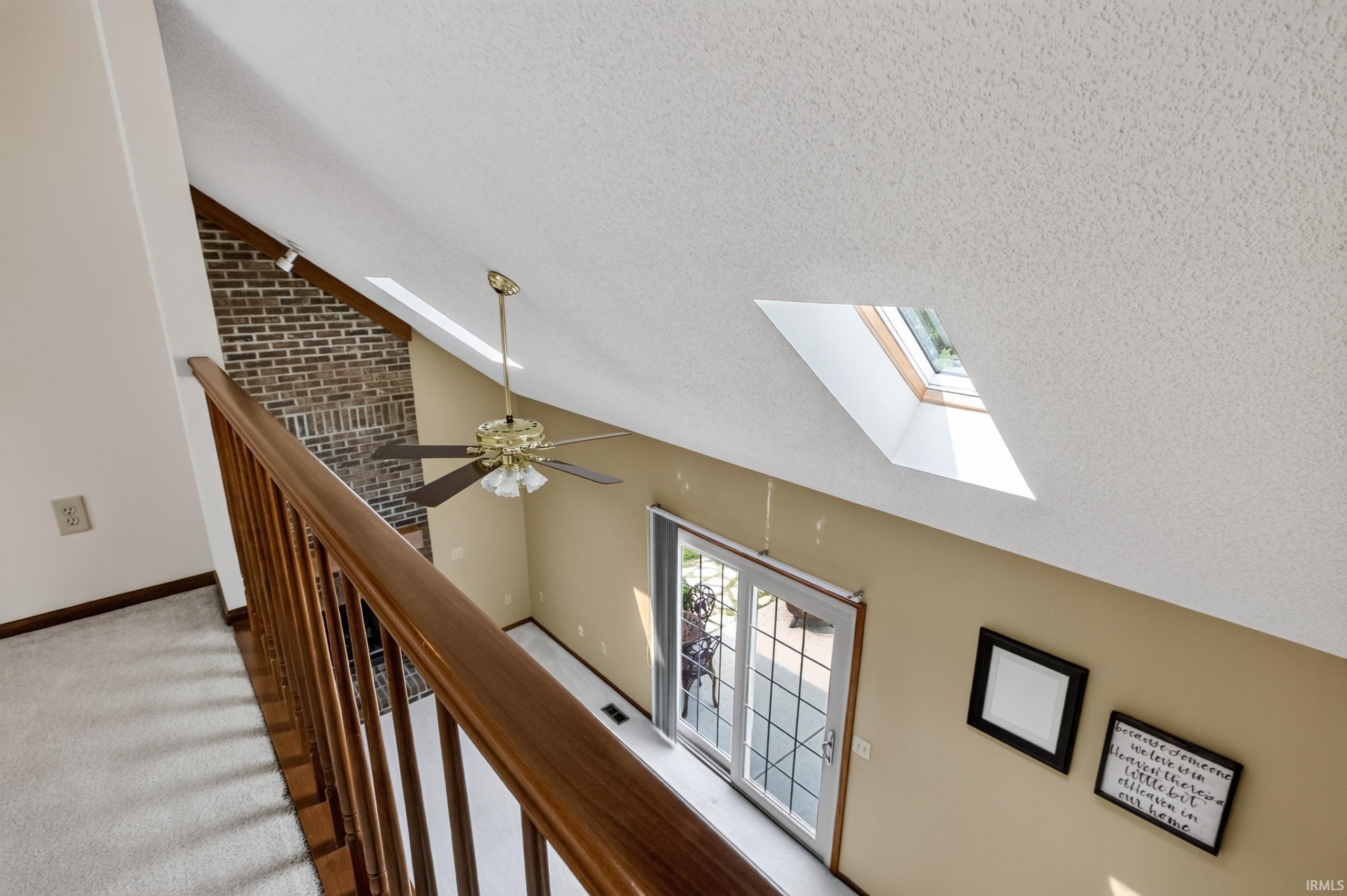 Overlooking a lower level with a brick accent wall and a ceiling fan