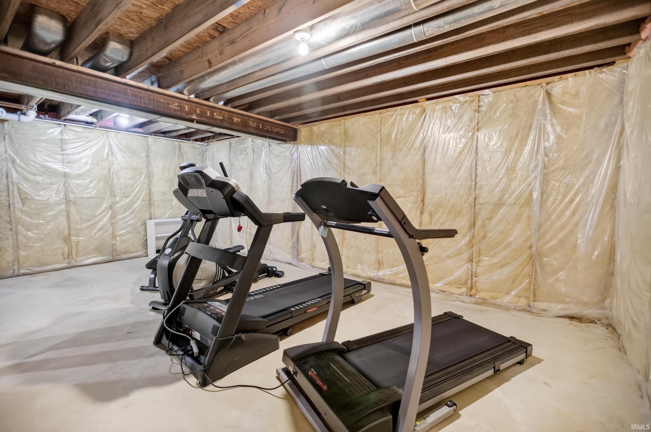 Unfinished basement offering exposed ceiling joists, concrete flooring, insulated walls, and overhead lighting