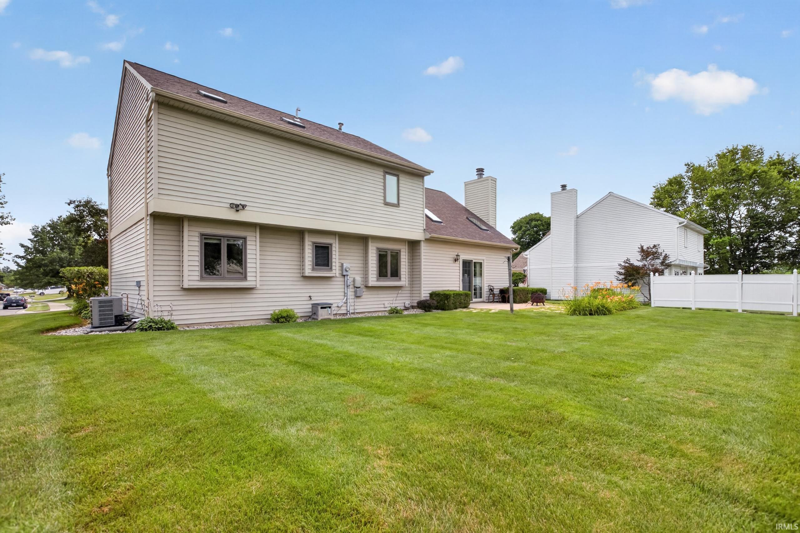 Expansive green lawn bordering a beige-sided residence with multiple windows