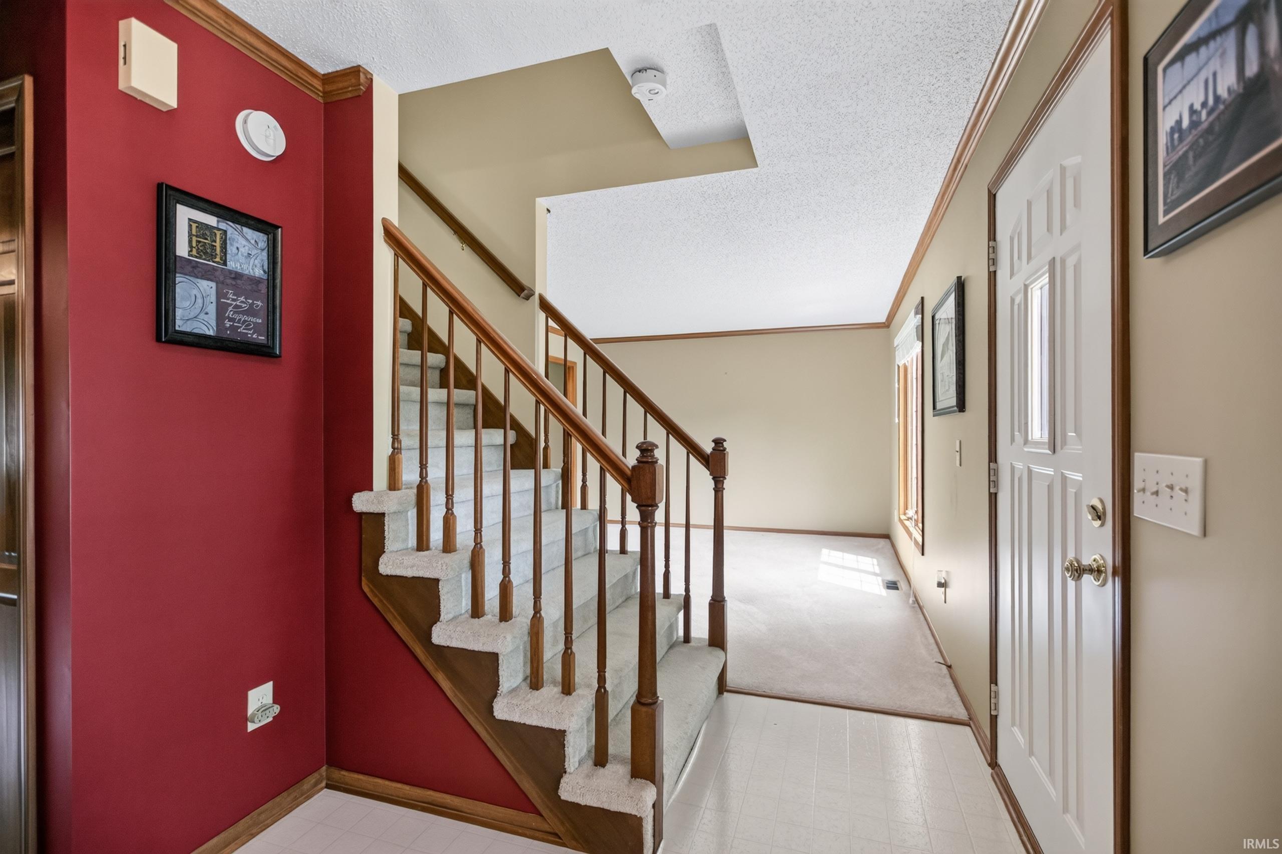 Entryway featuring a staircase with wood banister and carpeted treads, wood-finish trim, and a paneled entry door
