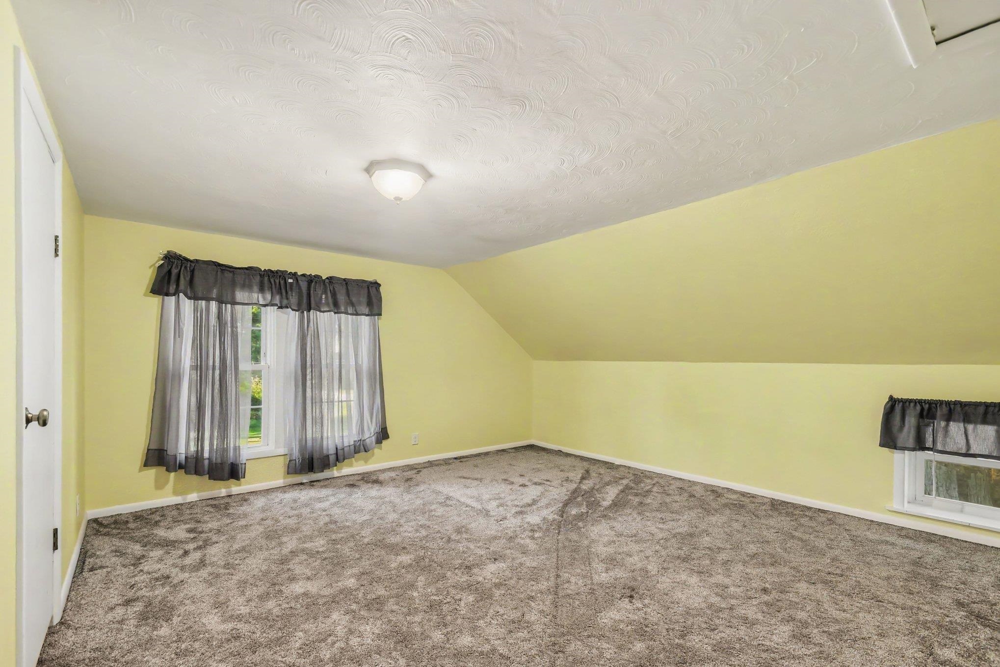 Carpeted flooring, sloped ceiling, and a flush mount ceiling light