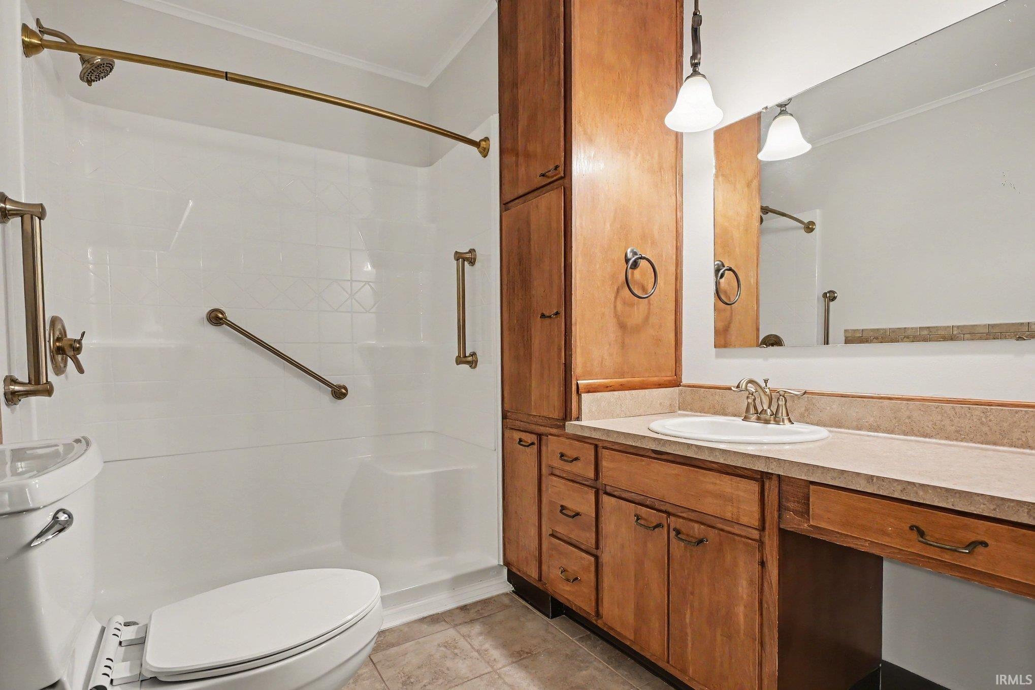 Bathroom featuring a single vanity with a countertop, integrated sink, and wood-finish cabinetry