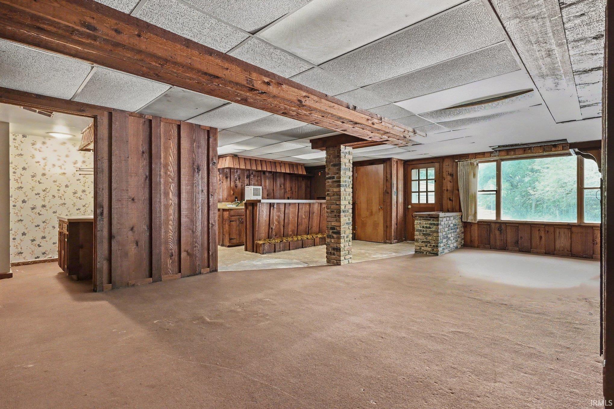 Spacious interior featuring wood paneling, exposed wood beams, and a drop ceiling