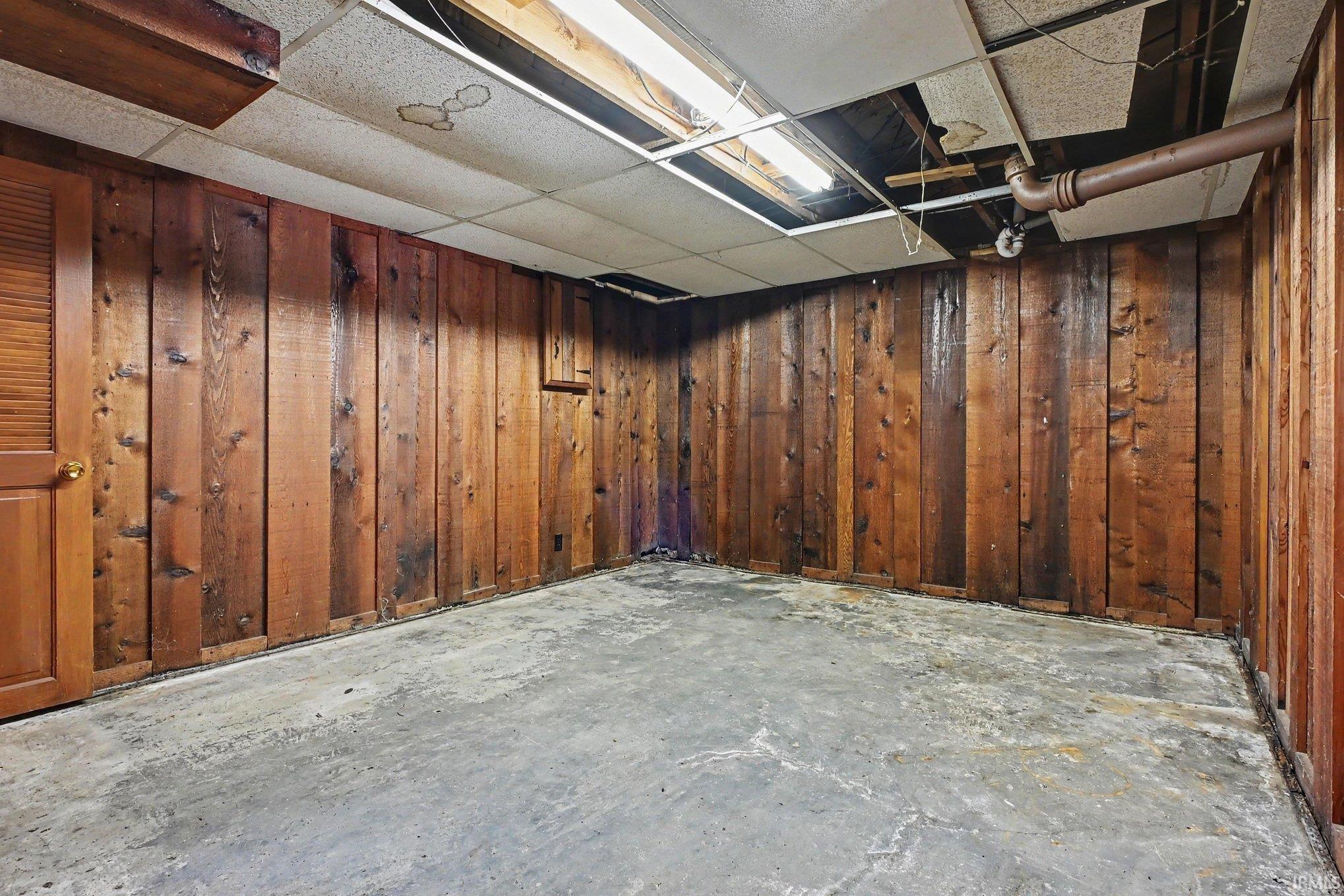 Room featuring wood paneling and a concrete floor