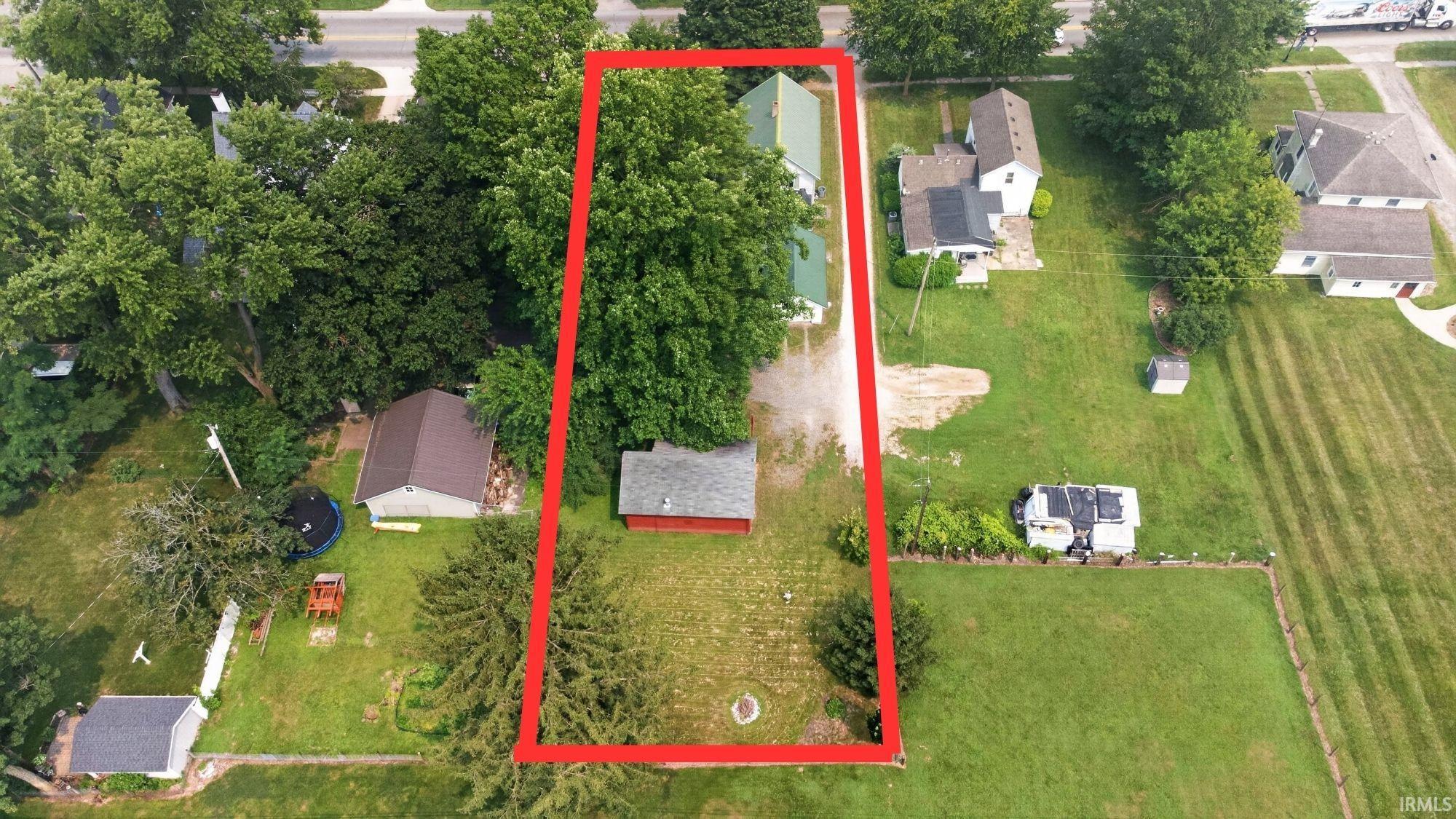 Spacious property featuring a residential structure, a detached shed, a secondary outbuilding, and mature trees providing substantial canopy coverage