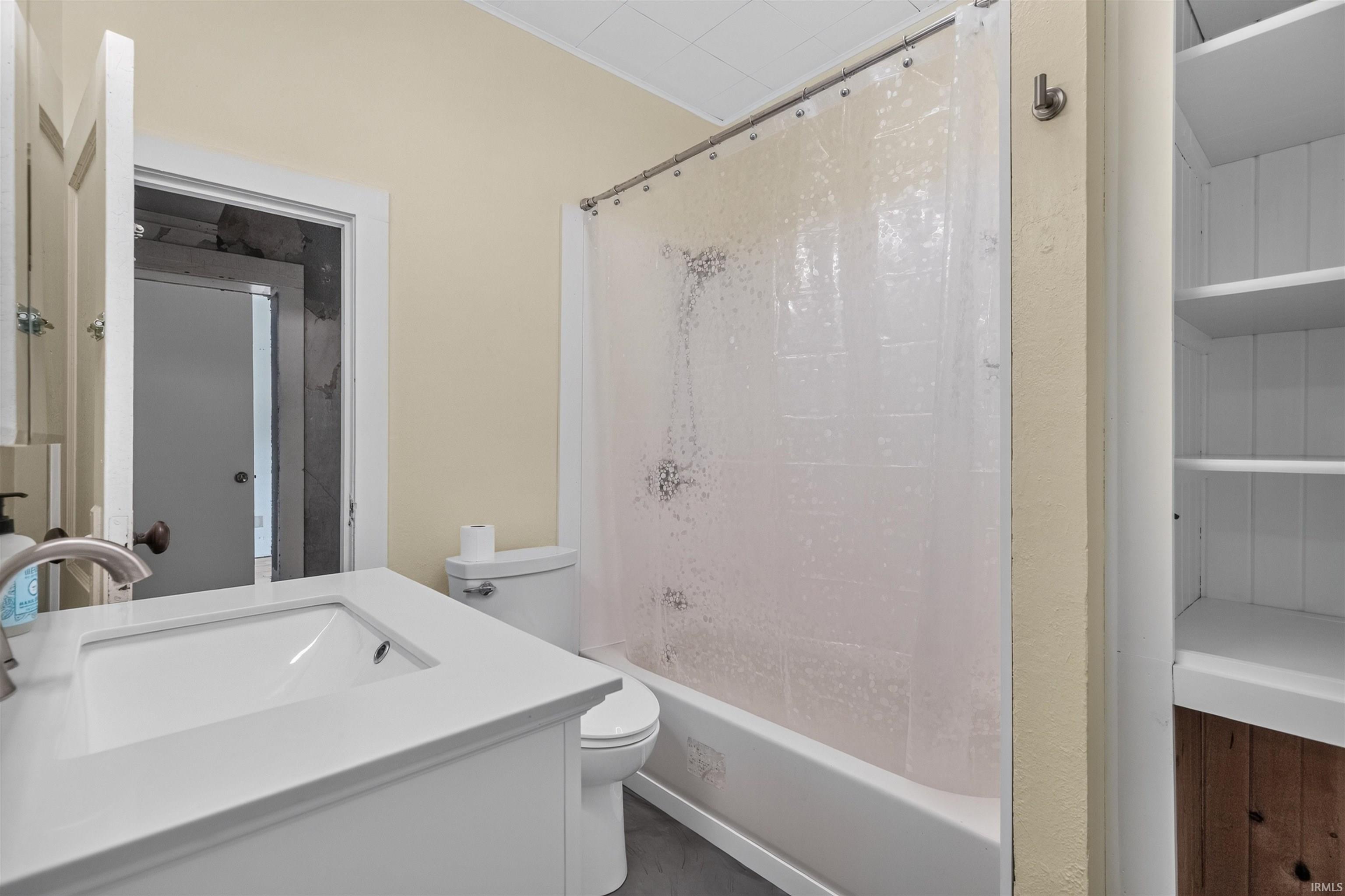 Bathroom featuring a white vanity with integrated sink, brushed nickel faucet, full bathtub with shower, and built-in shelving