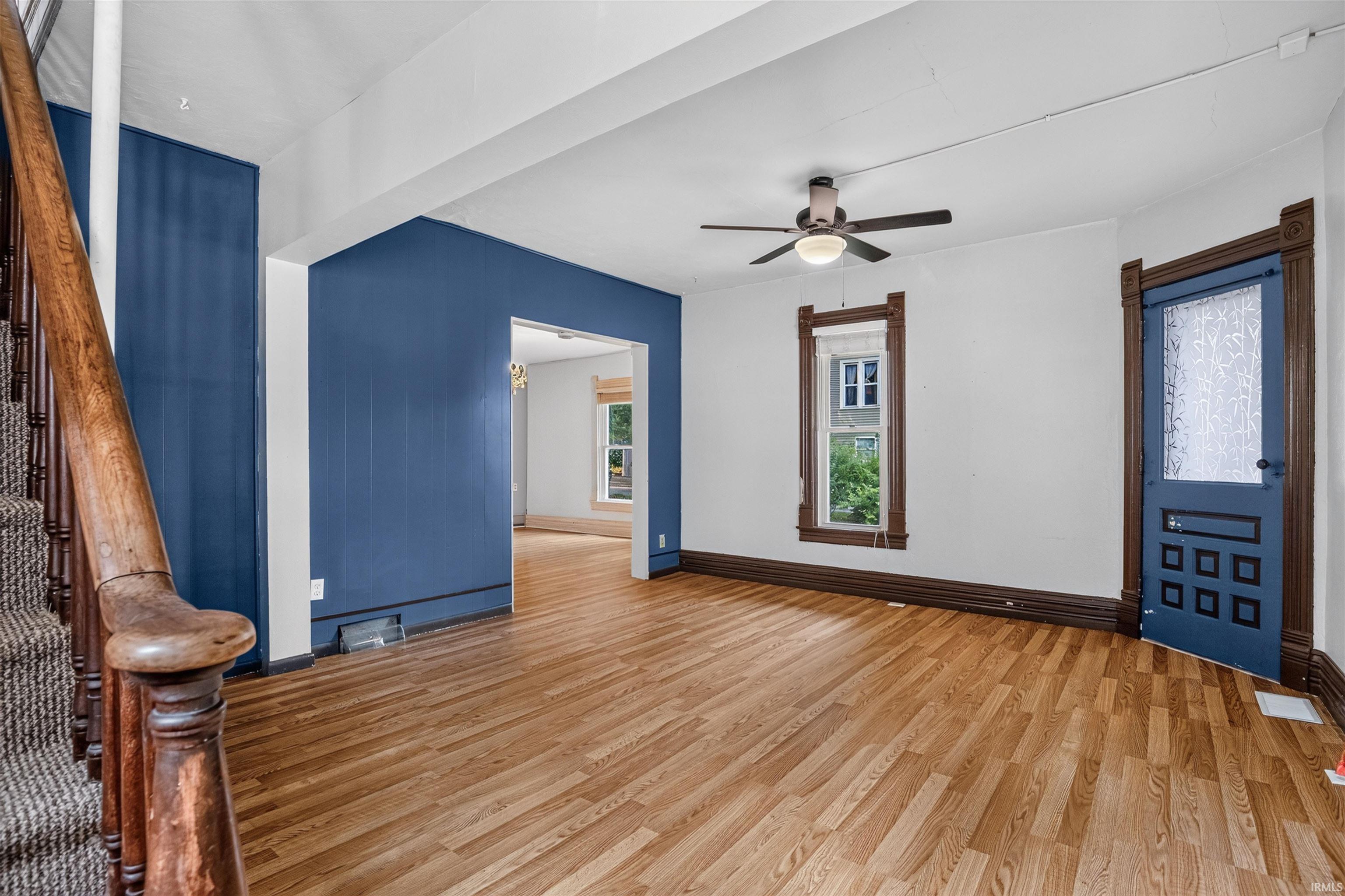 Open concept room featuring wood-finish flooring, a ceiling fan, and painted accent walls